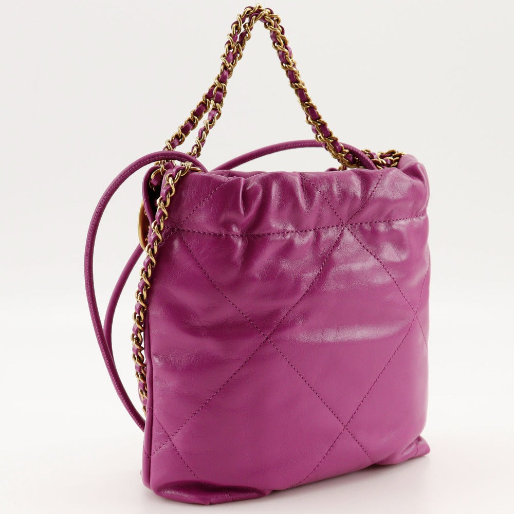 Purple quilted handbag with gold chain handle on a white background