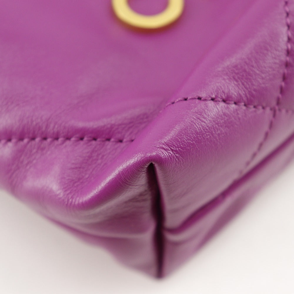 Close-up of a purple leather product with a gold buckle on a white background