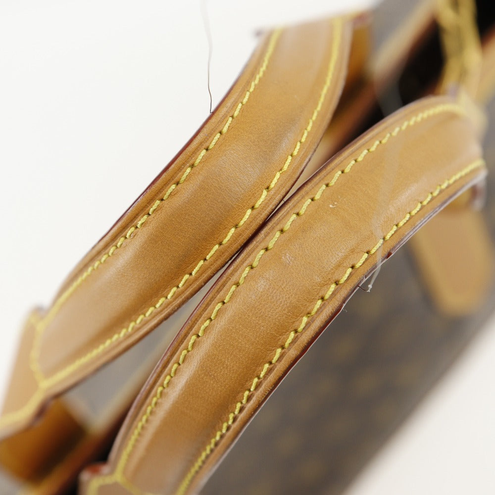 Close-up of a brown leather handbag with yellow stitching on a white background