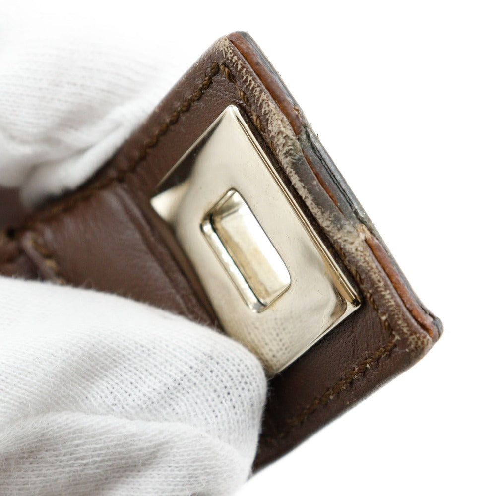 Close-up of a brown leather belt with a gold buckle on a white background