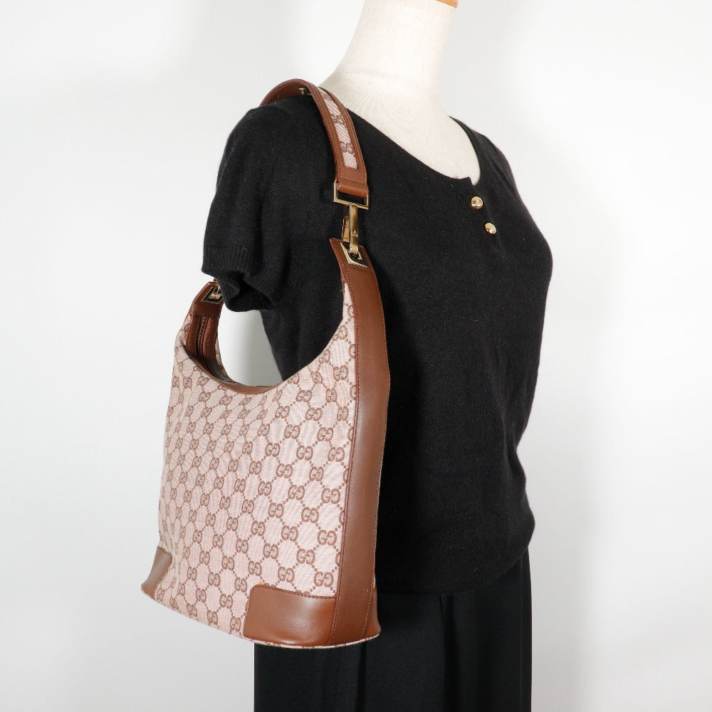 Mannequin wearing a black outfit with a patterned handbag on a white background