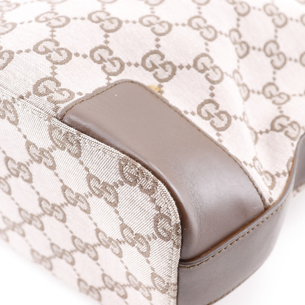 Close-up of a Gucci handbag with monogram pattern and brown leather trim.
