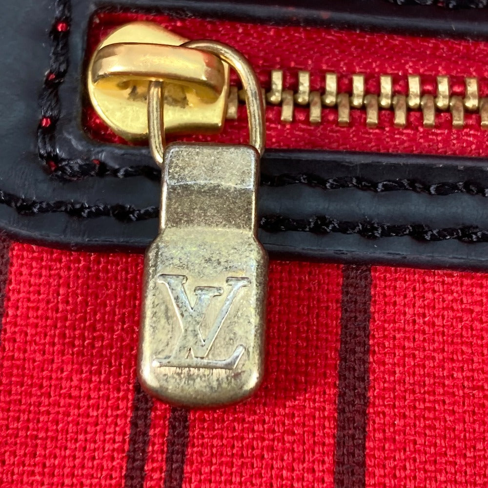 Close-up of a gold zipper pull with Louis Vuitton logo on a red fabric background