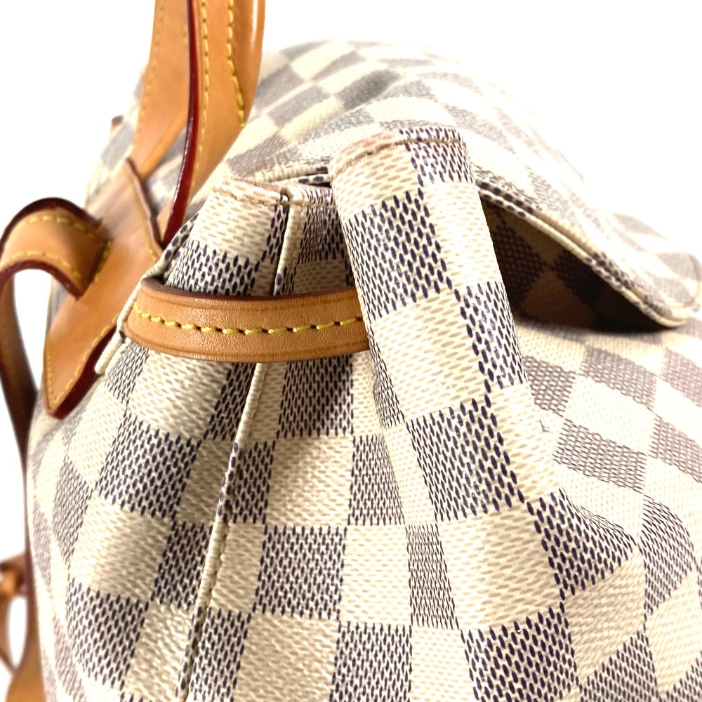 Close-up of a checkered handbag with brown leather handles on a white background