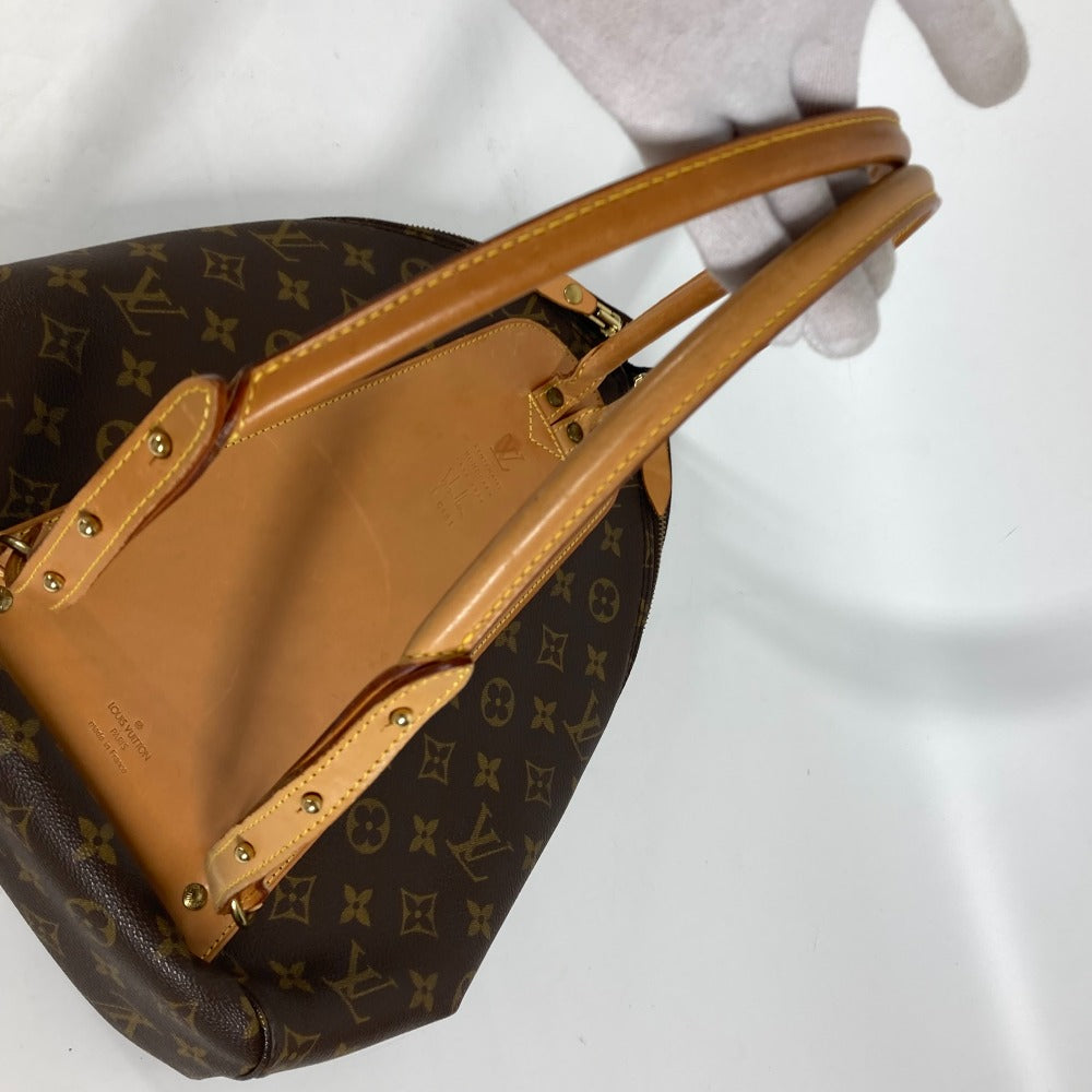 Louis Vuitton handbag with monogram pattern held by a gloved hand on a white background