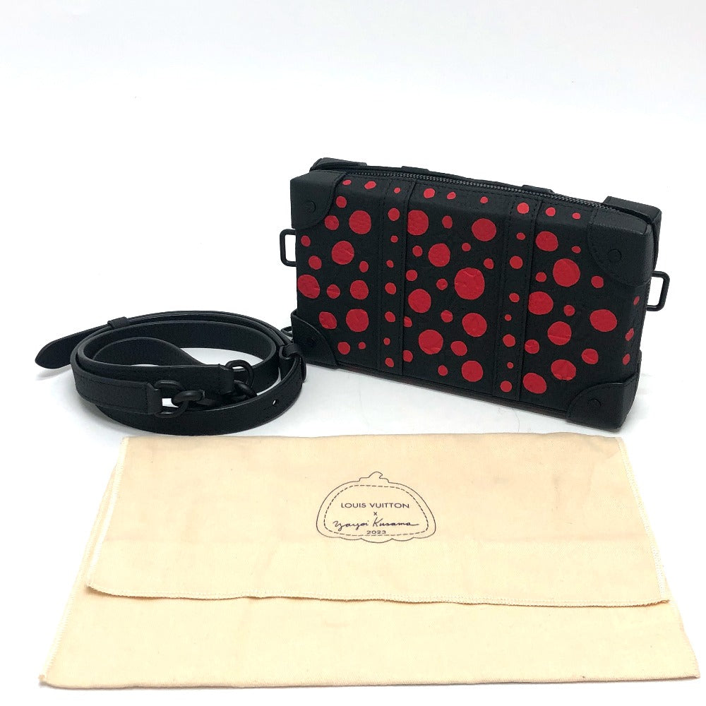 Black clutch bag with red polka dots and black strap on a white background