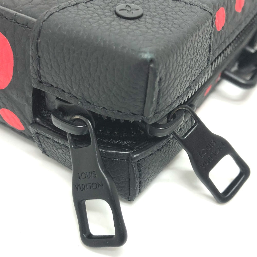 Close-up of a black leather bag with red polka dots and 'Louis Vuitton' logo.