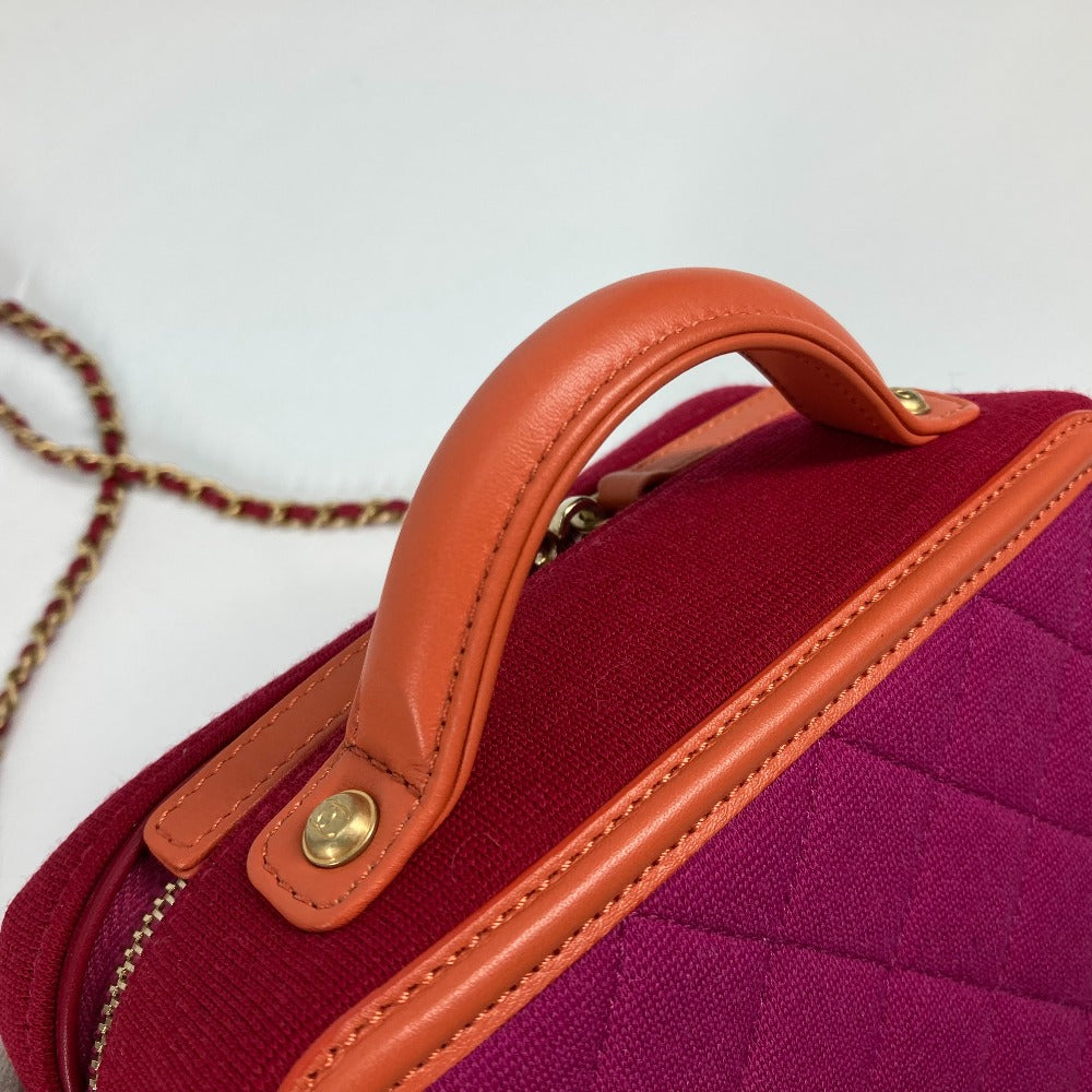 Red handbag with orange handle and trim on a light gray background