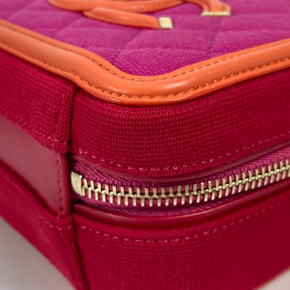 Close-up of a pink and orange quilted handbag with gold zipper.