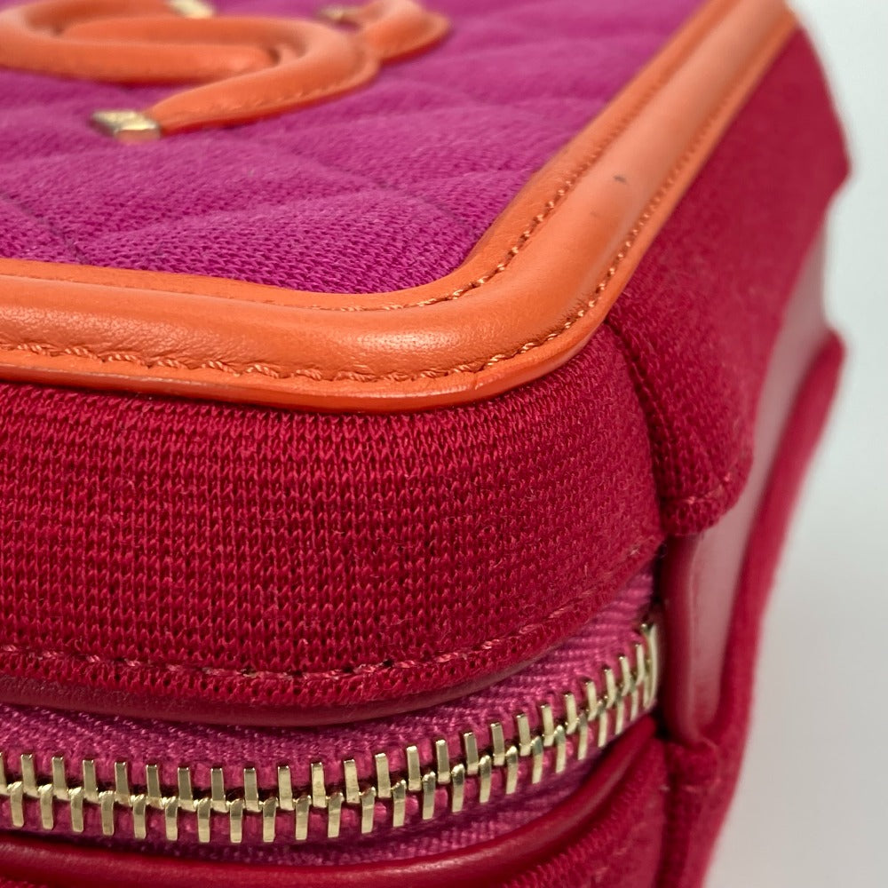 Close-up of a pink bag with orange trim and gold zippers on a white background