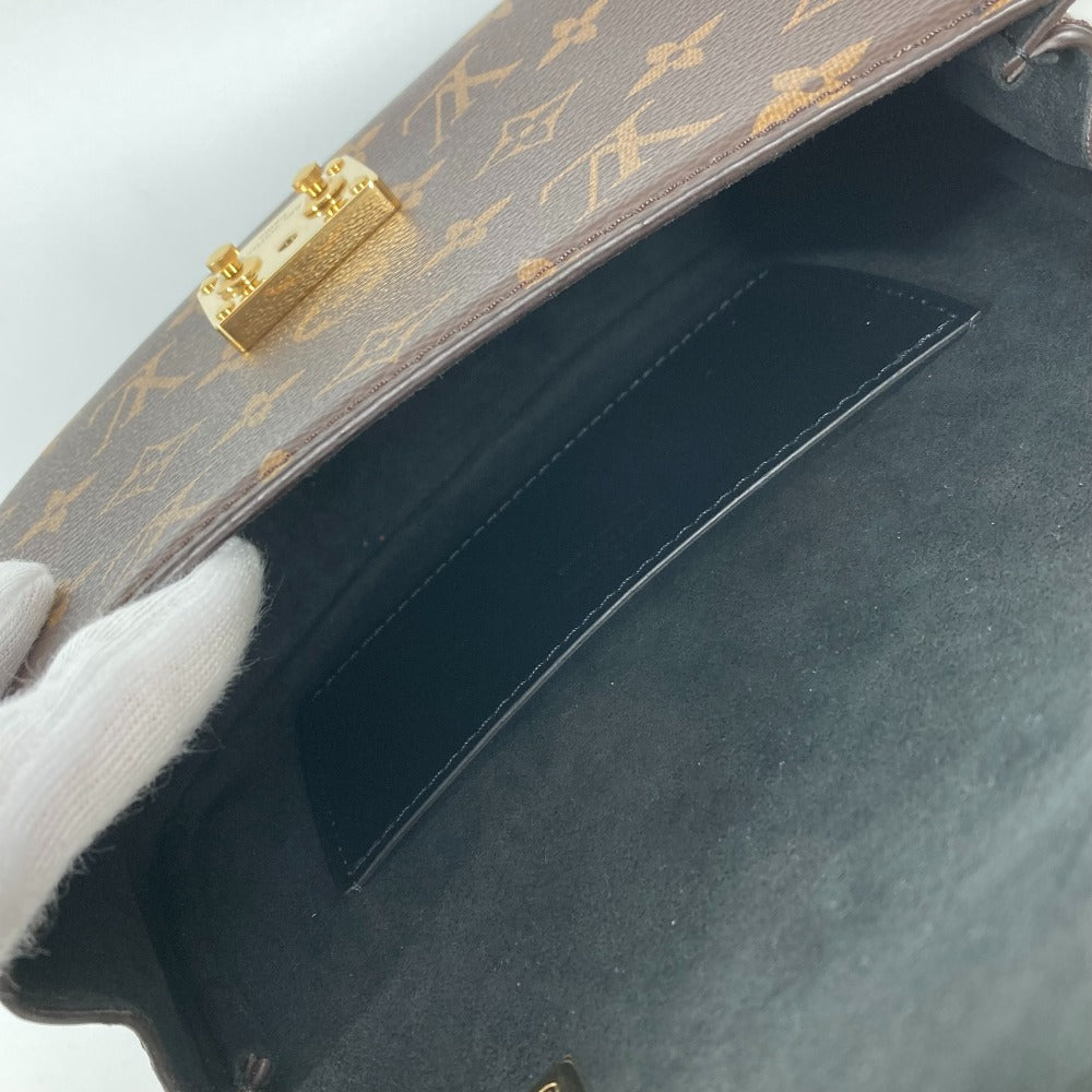 Close-up of a handbag with gold accents and a gloved hand holding it.