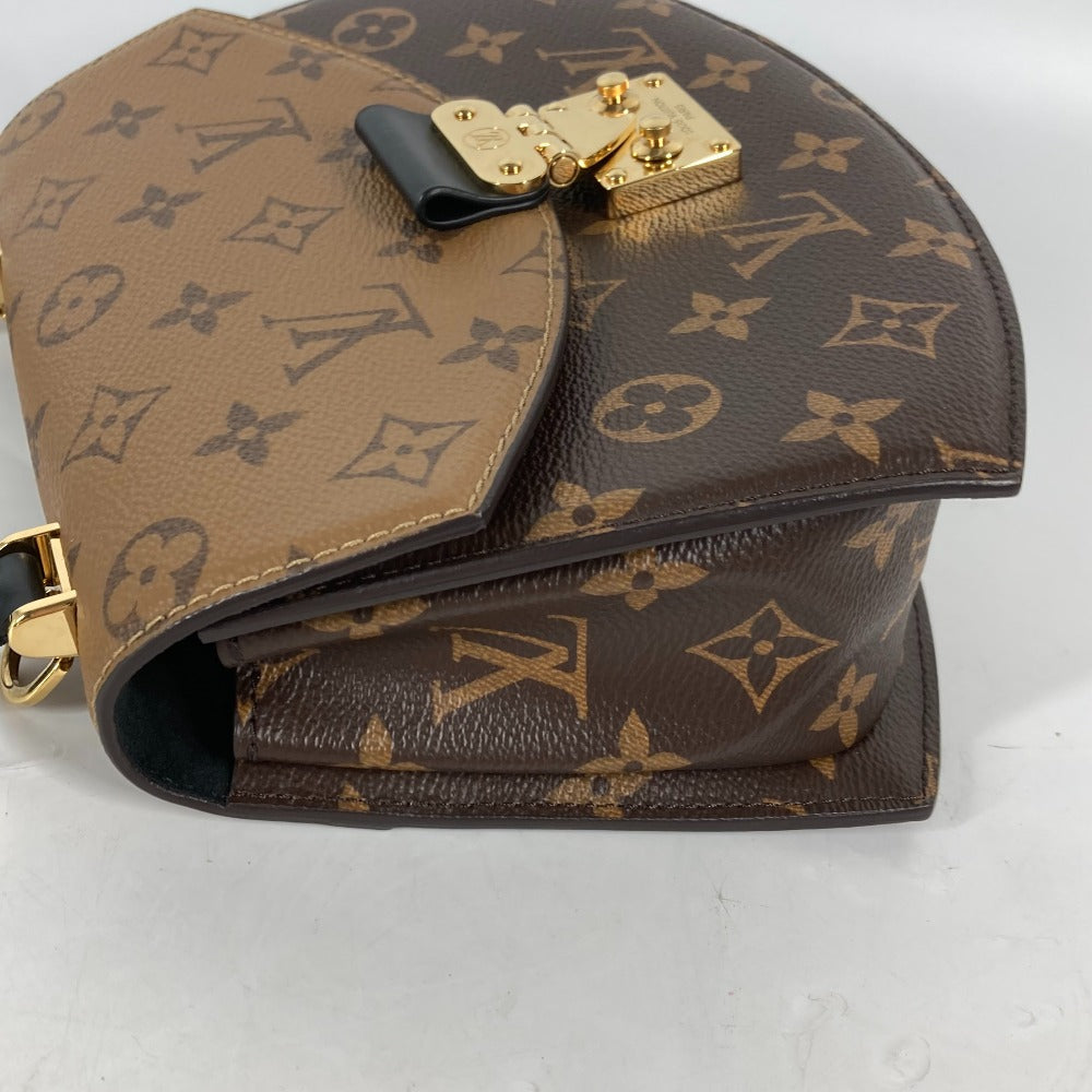 Louis Vuitton monogram handbag with gold hardware on a light gray background