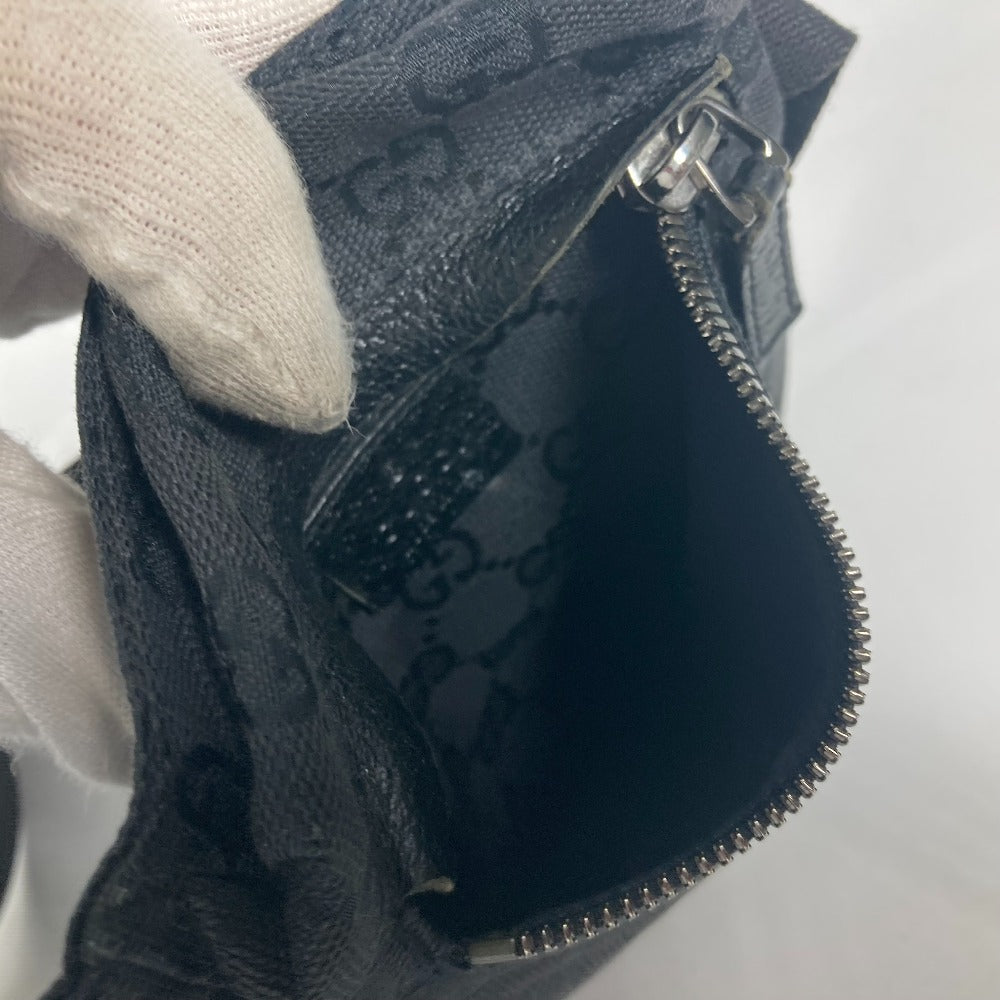 Close-up of a textured black bag with a zipper, held by a person wearing white gloves.