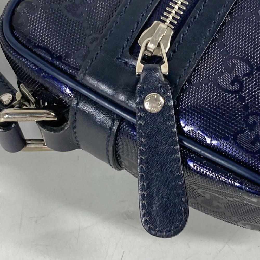 Close-up of a navy blue textured bag with a strap and zipper on a light gray background