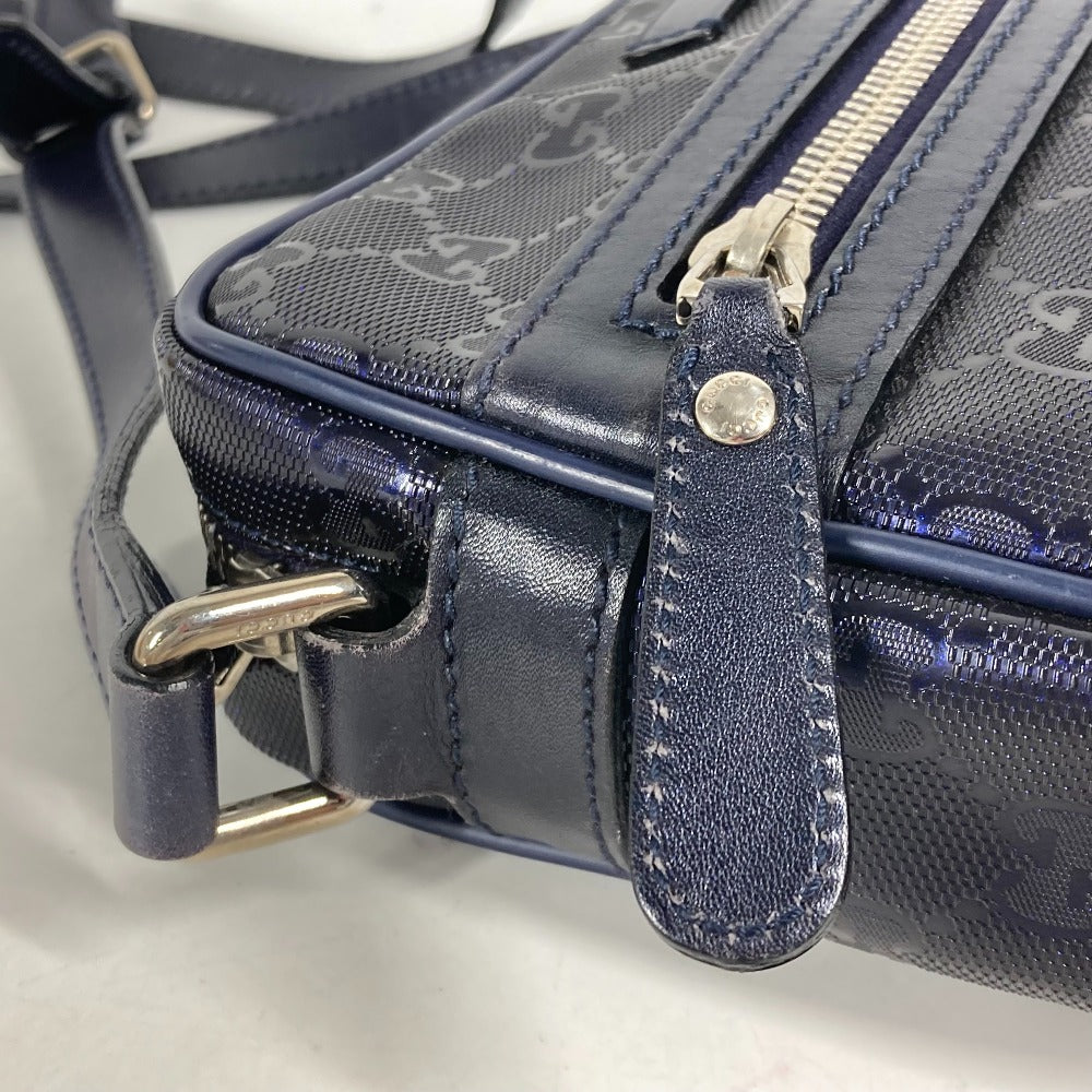 Close-up of a navy blue handbag with a textured surface and visible brand logo.