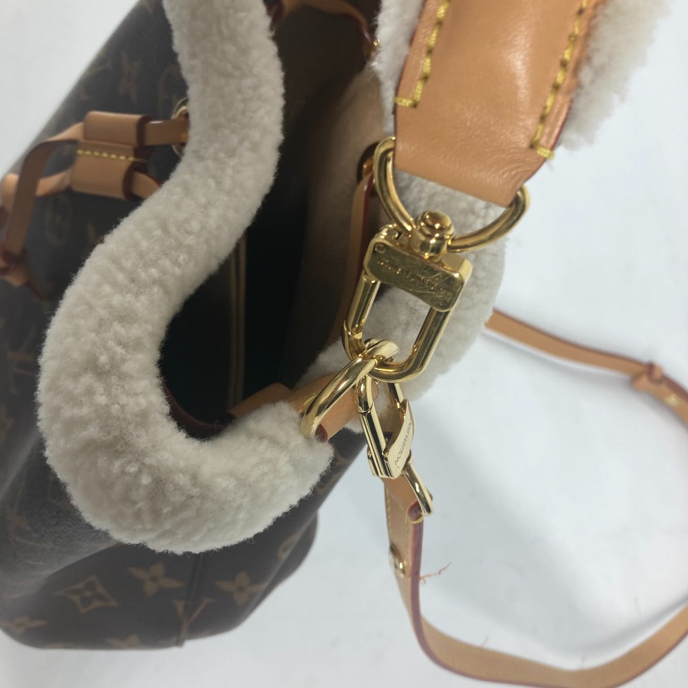 Close-up of a Louis Vuitton handbag with a gold keychain on a white background