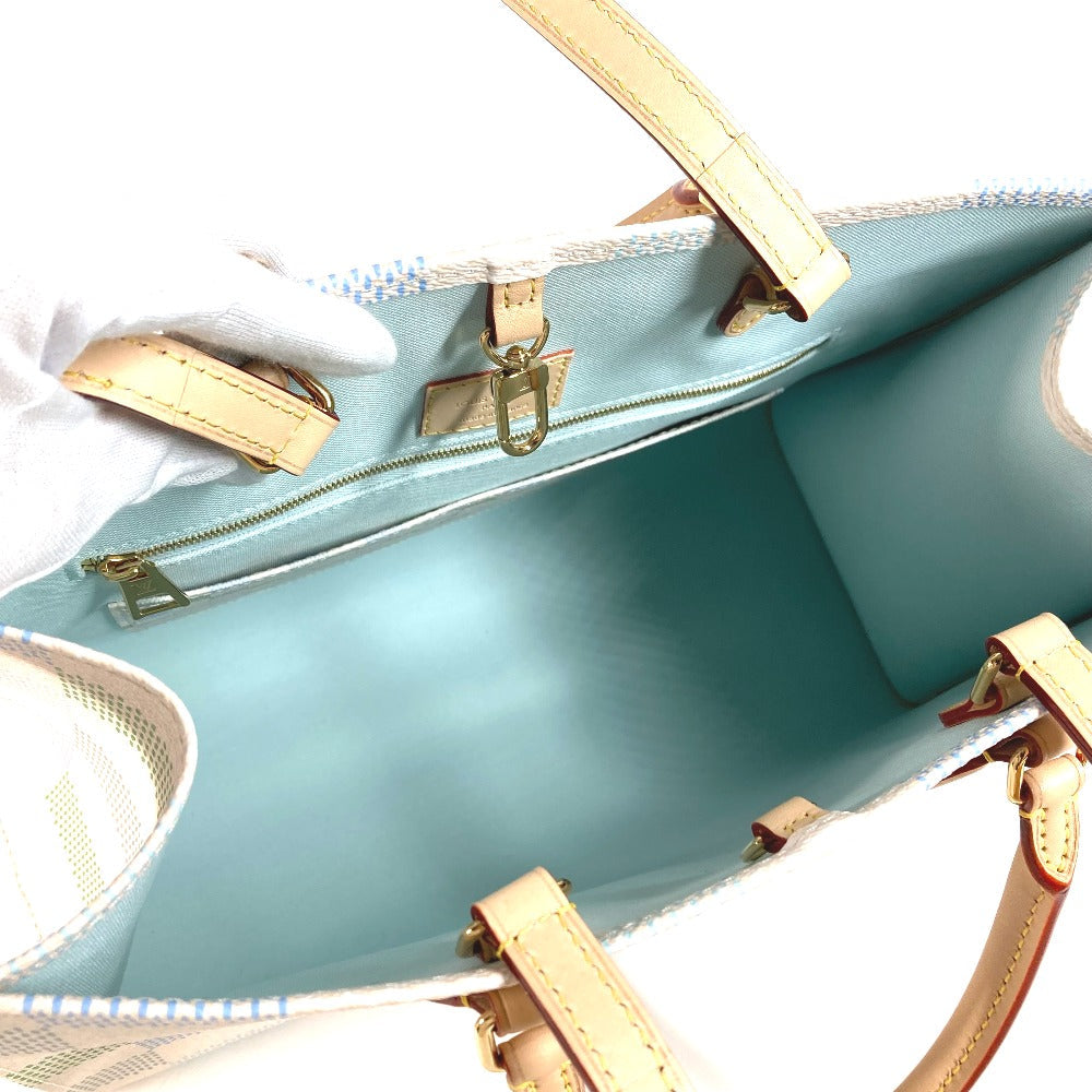 Close-up of a light blue handbag with beige handles and trim on a white background