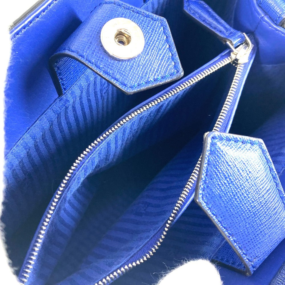 Close-up of a blue textured handbag with a gold zipper and button.