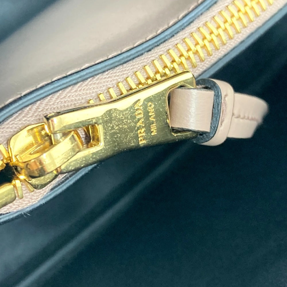 Close-up of a gold Prada zipper on a handbag.