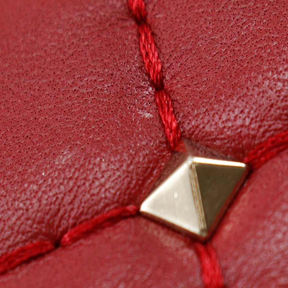 Close-up of a red leather surface with a gold triangular metal object.