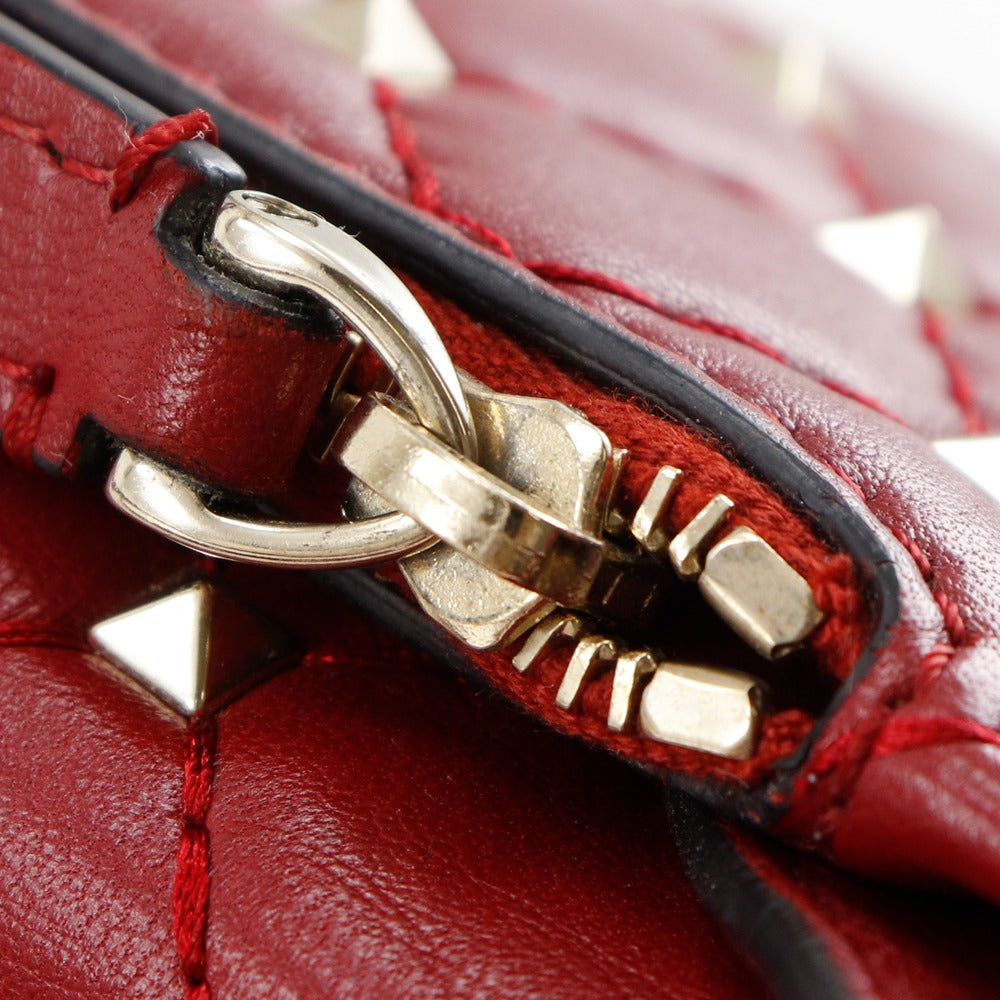 Close-up of a red leather bag with a gold zipper pull.