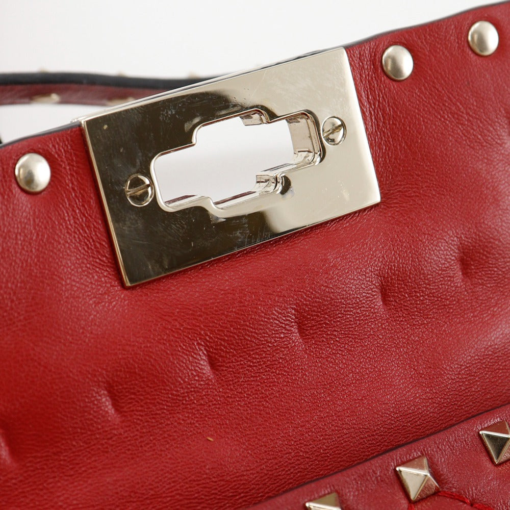 Close-up of a red leather handbag with a silver clasp and studs.