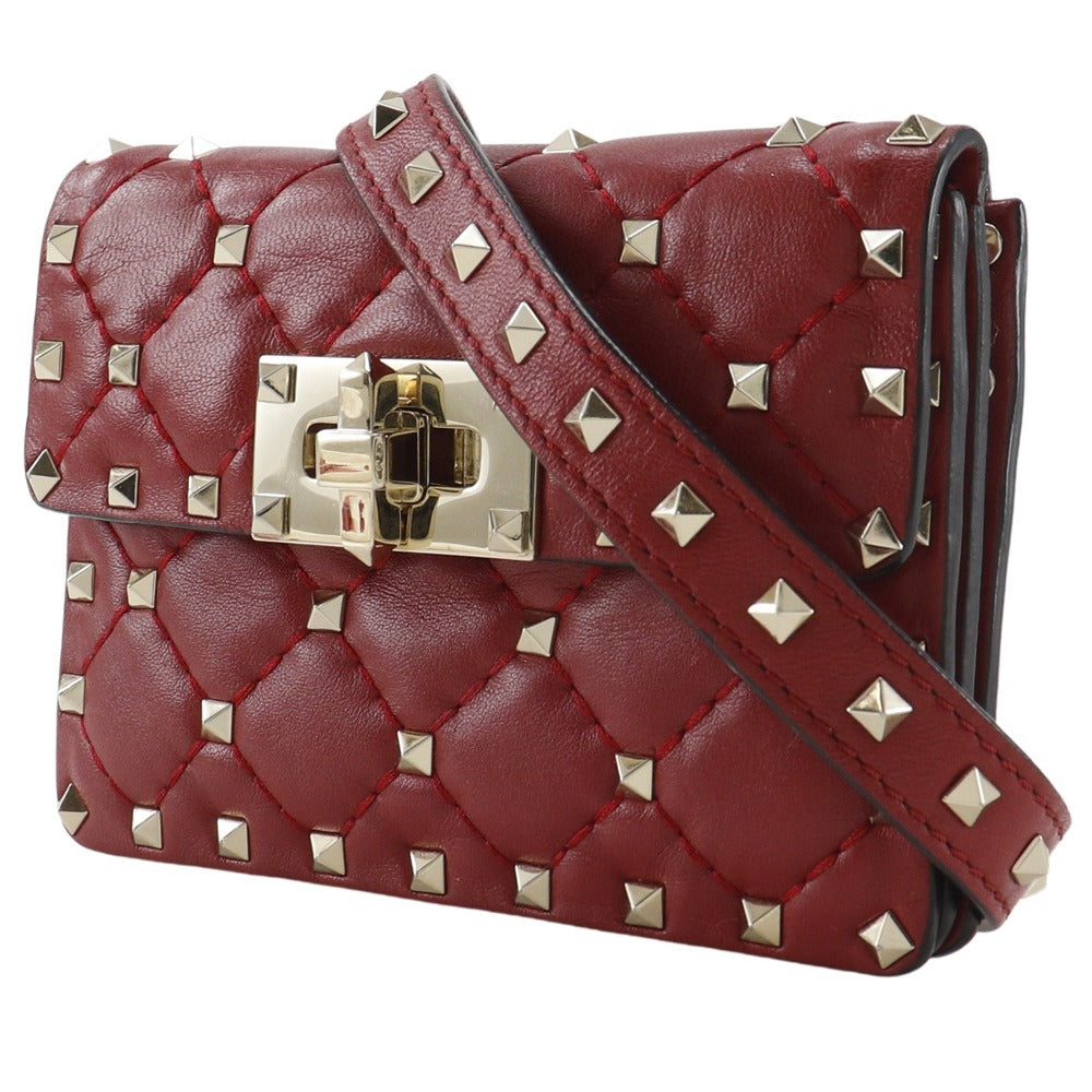 Red quilted handbag with gold studs and a gold clasp on a white background