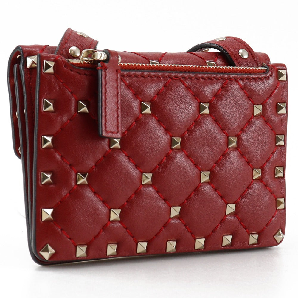 Red quilted handbag with gold studs on a white background