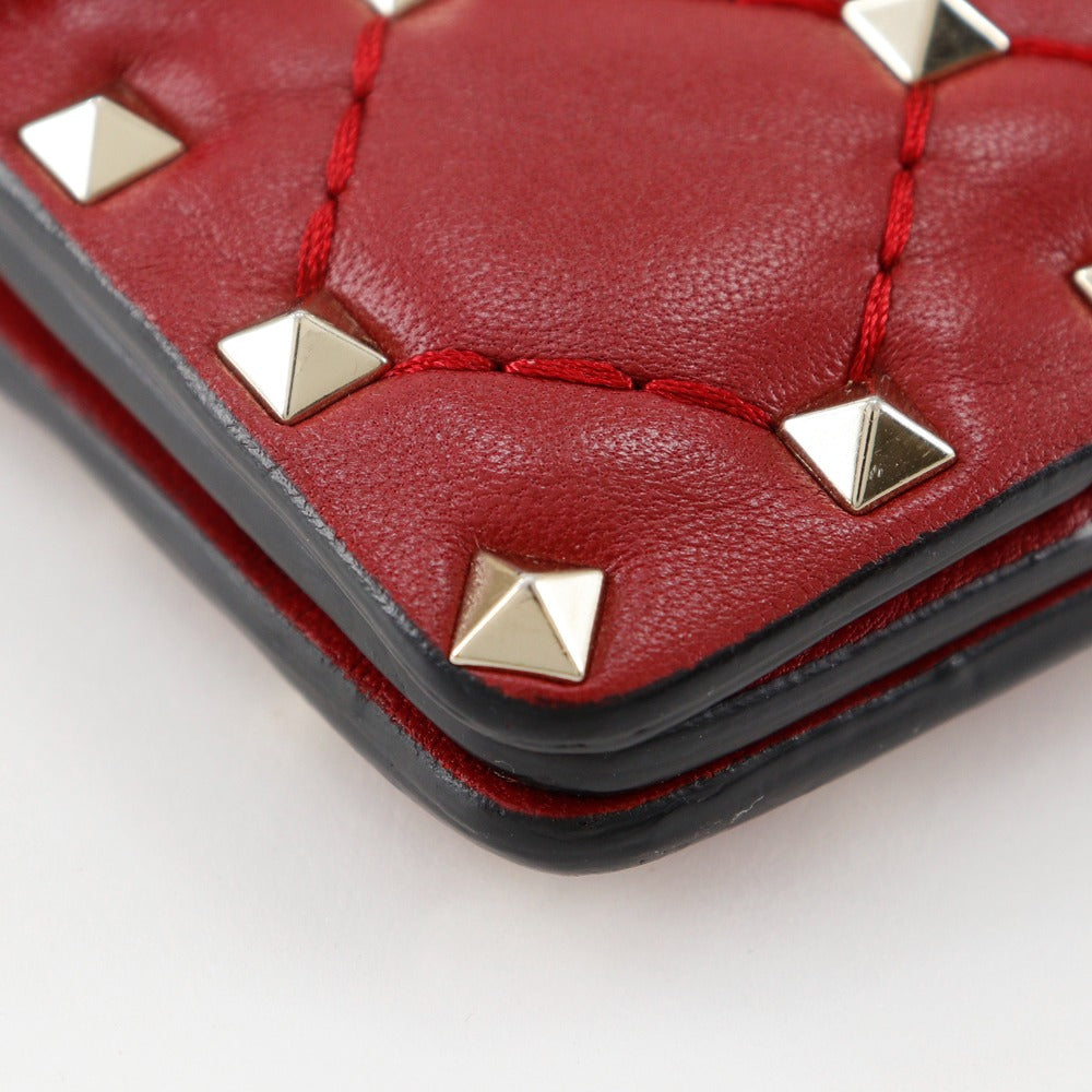 Red leather wallet with gold studs on a white background