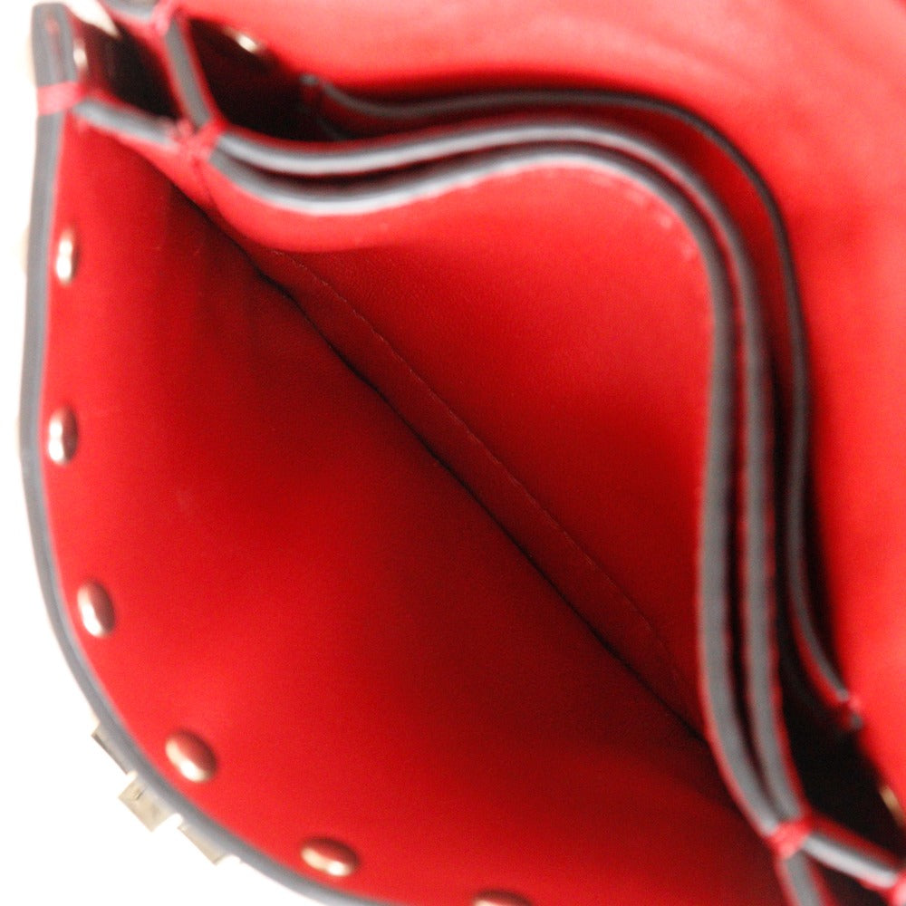 Close-up of a red leather saddle with black stitching on a white background