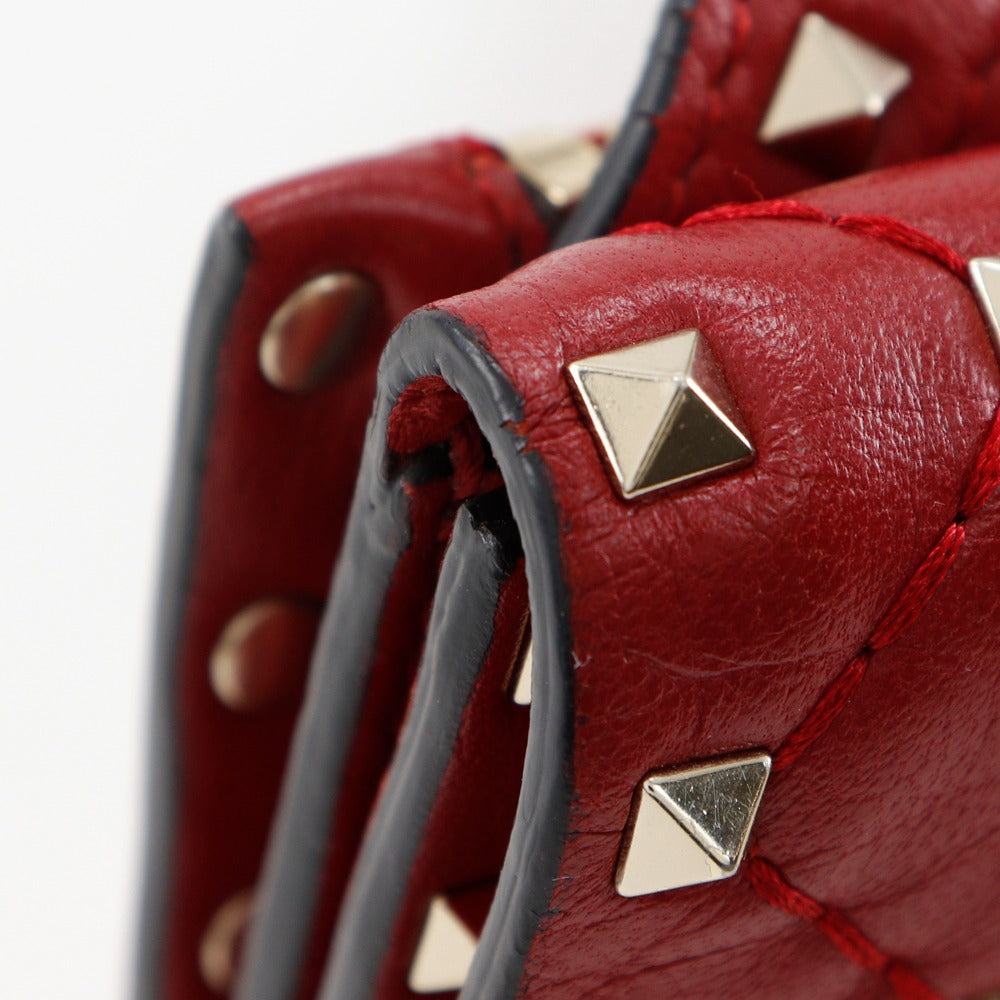 Close-up of a red leather handbag with gold studs on a white background