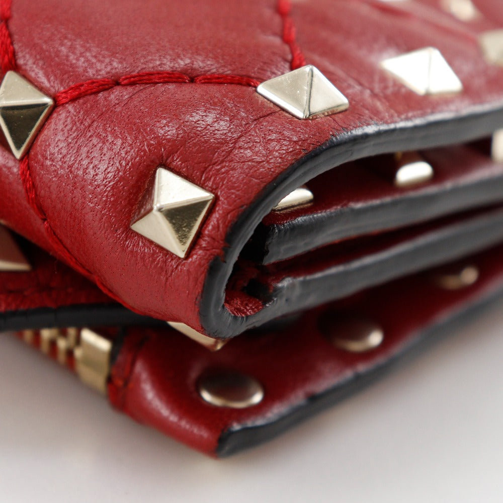 Red leather wallet with gold studs on a white background