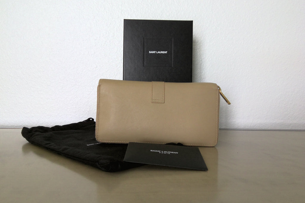 Beige wallet with black box and paper on a light surface