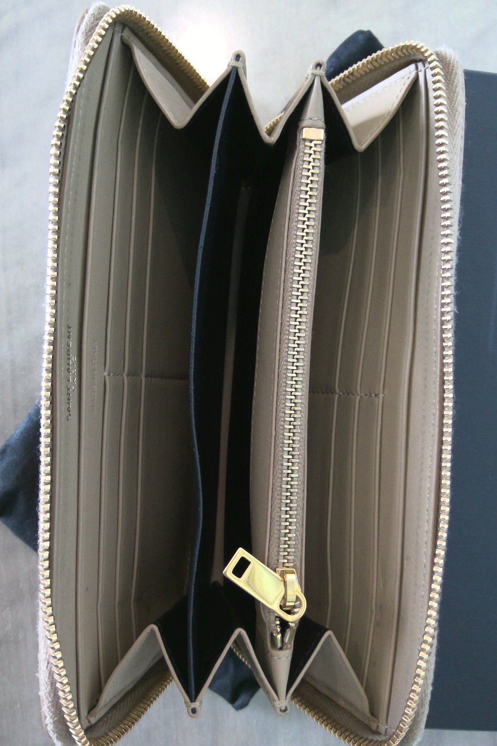 Open beige wallet with gold zipper on a gray background