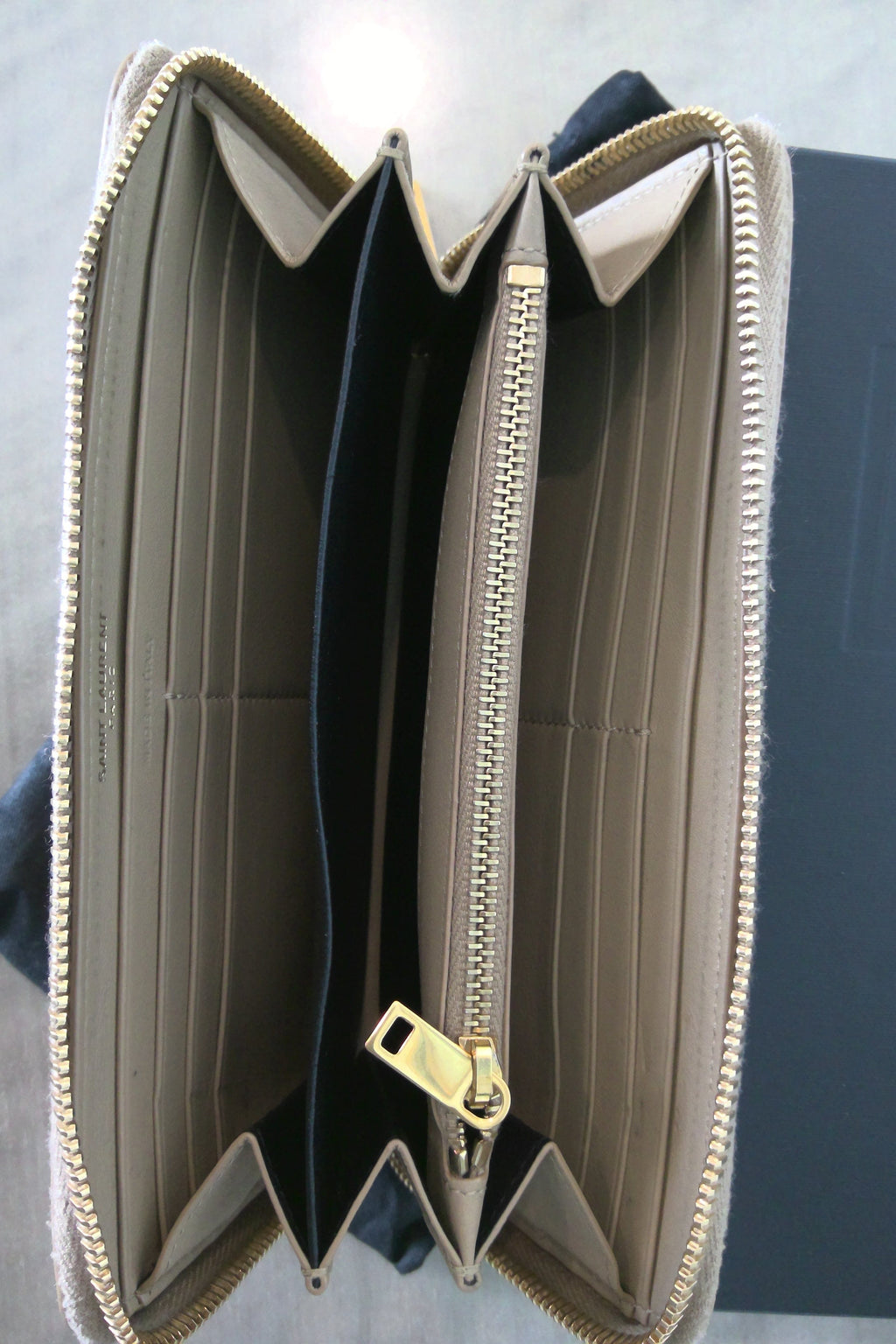 Open beige wallet with gold zipper on a gray background