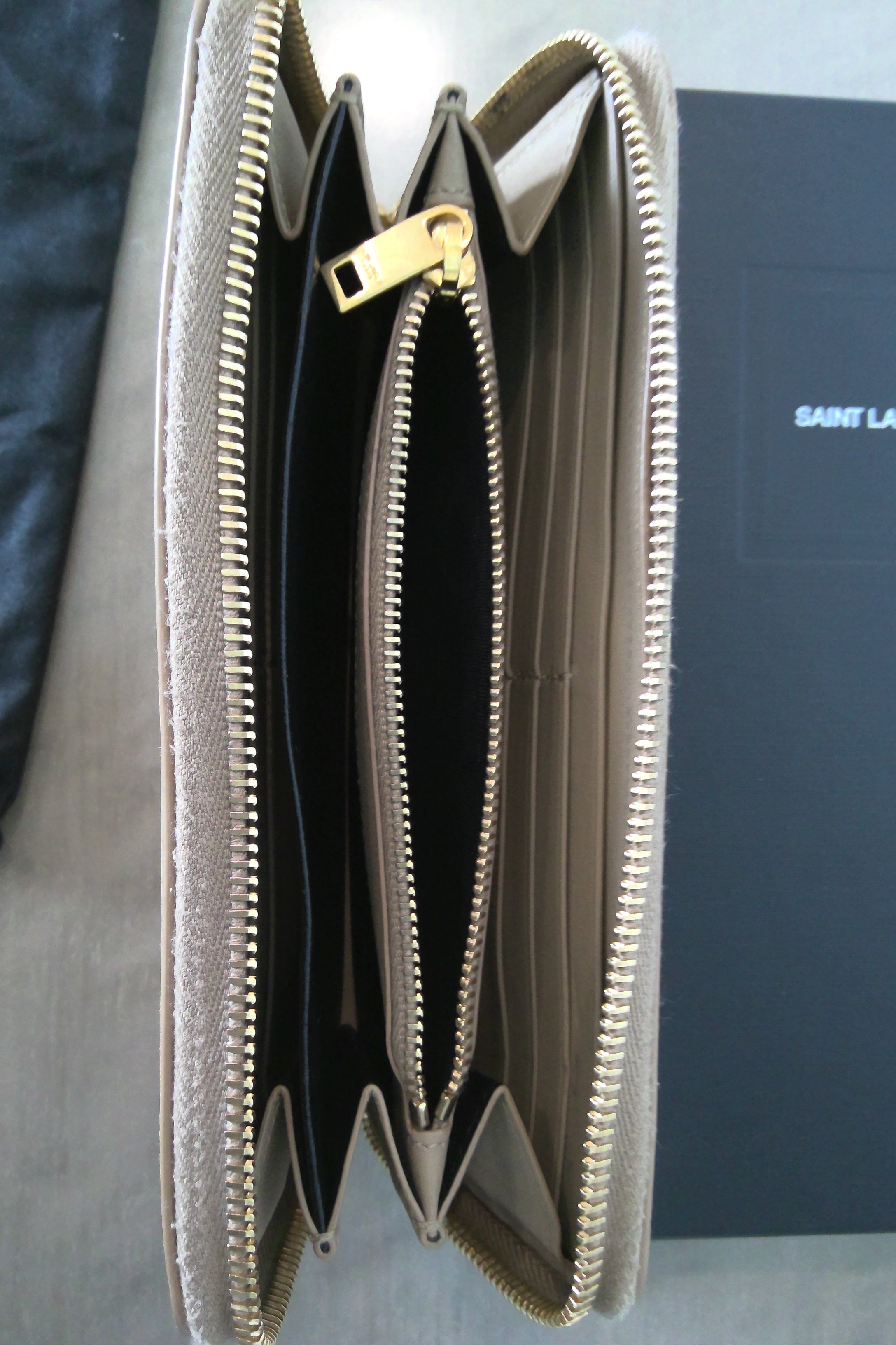 Open beige wallet with gold zipper on a dark surface