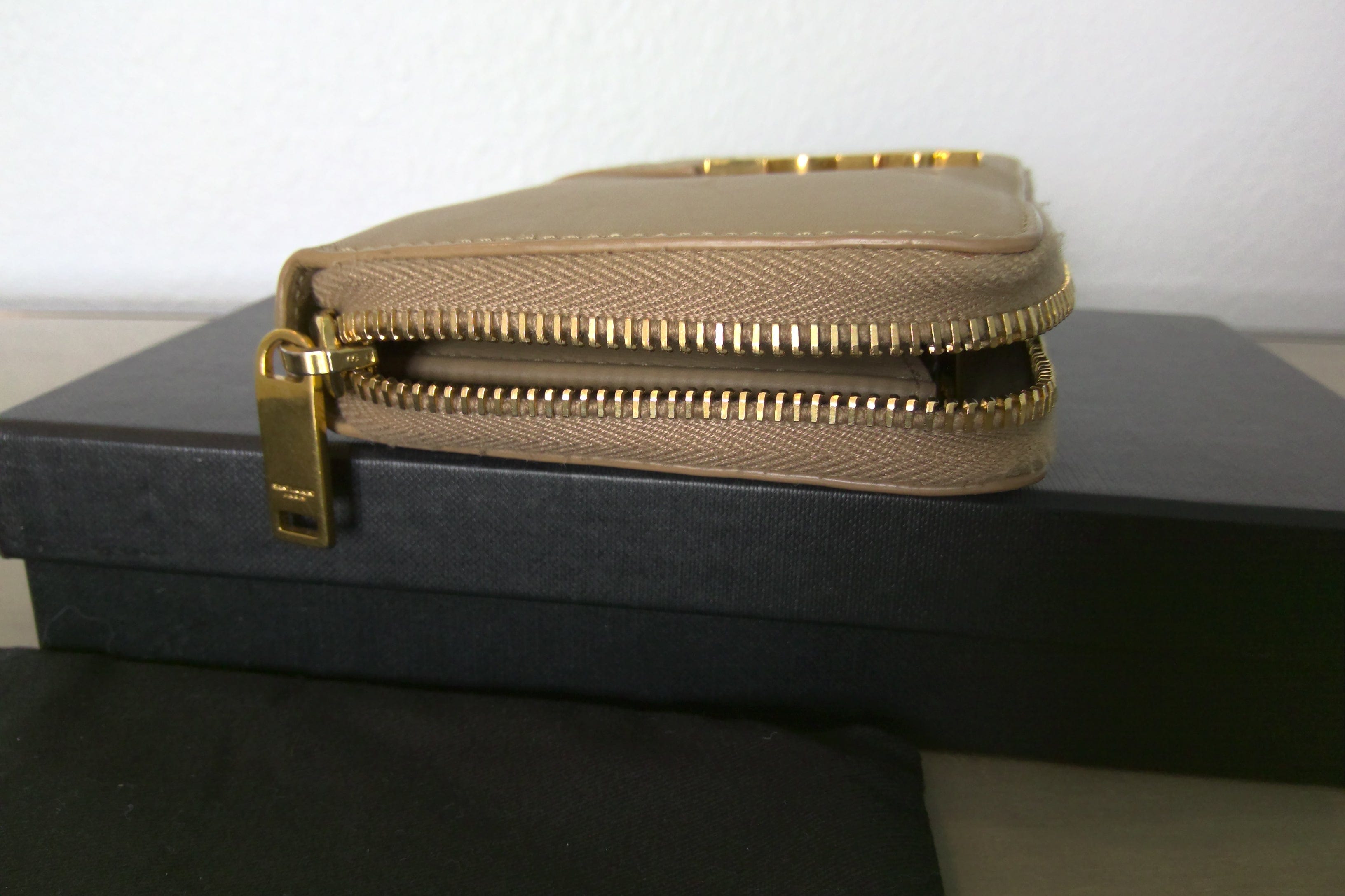 Gold clutch bag with a gold zipper on a black box