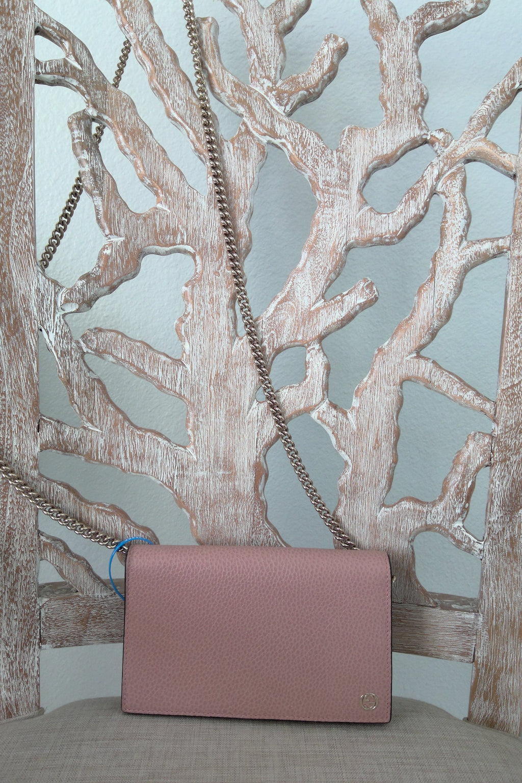 Pink handbag with a chain strap on a decorative metal surface