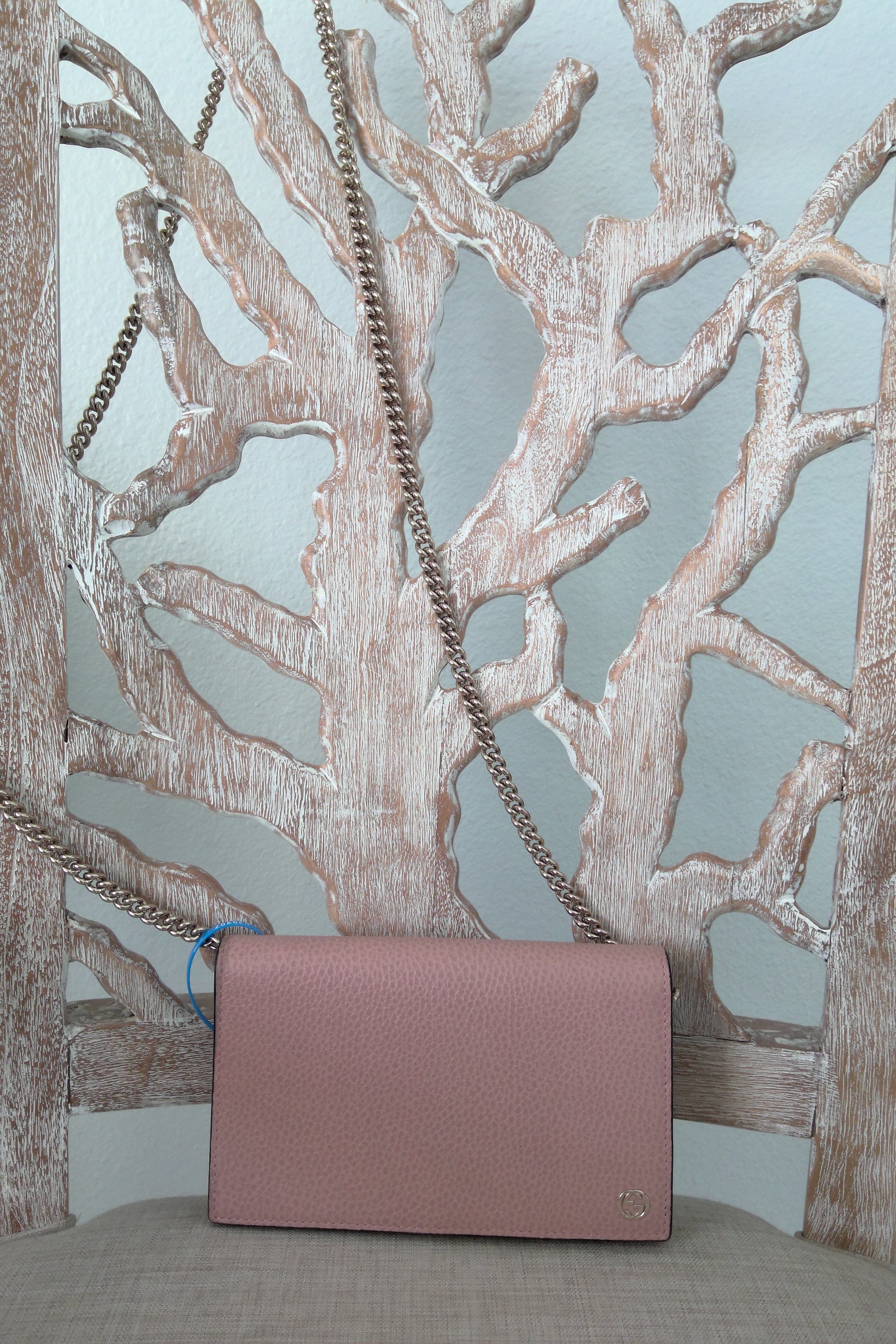Pink handbag with a chain strap on a decorative metal surface