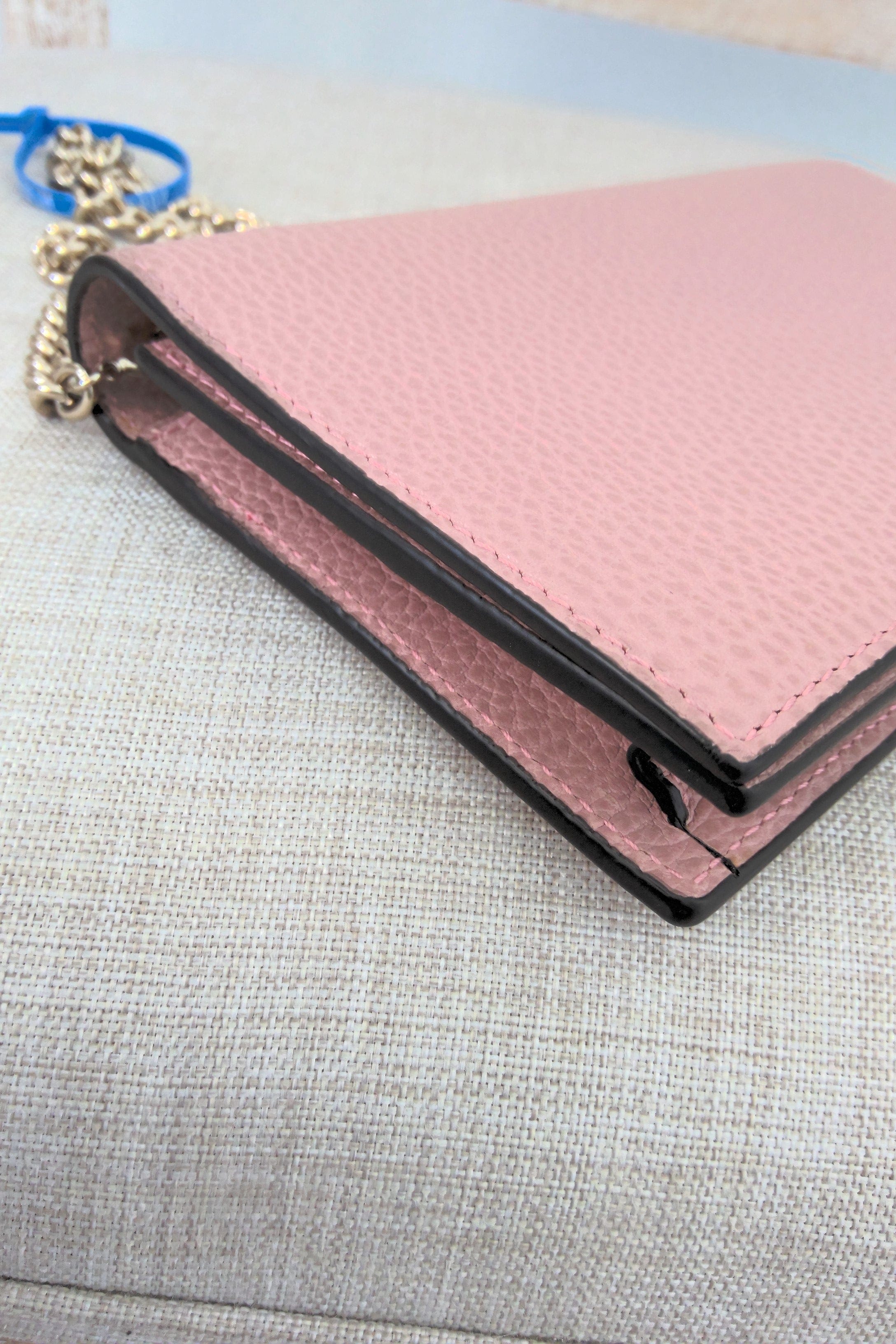 Pink wallet with black trim on a gray surface