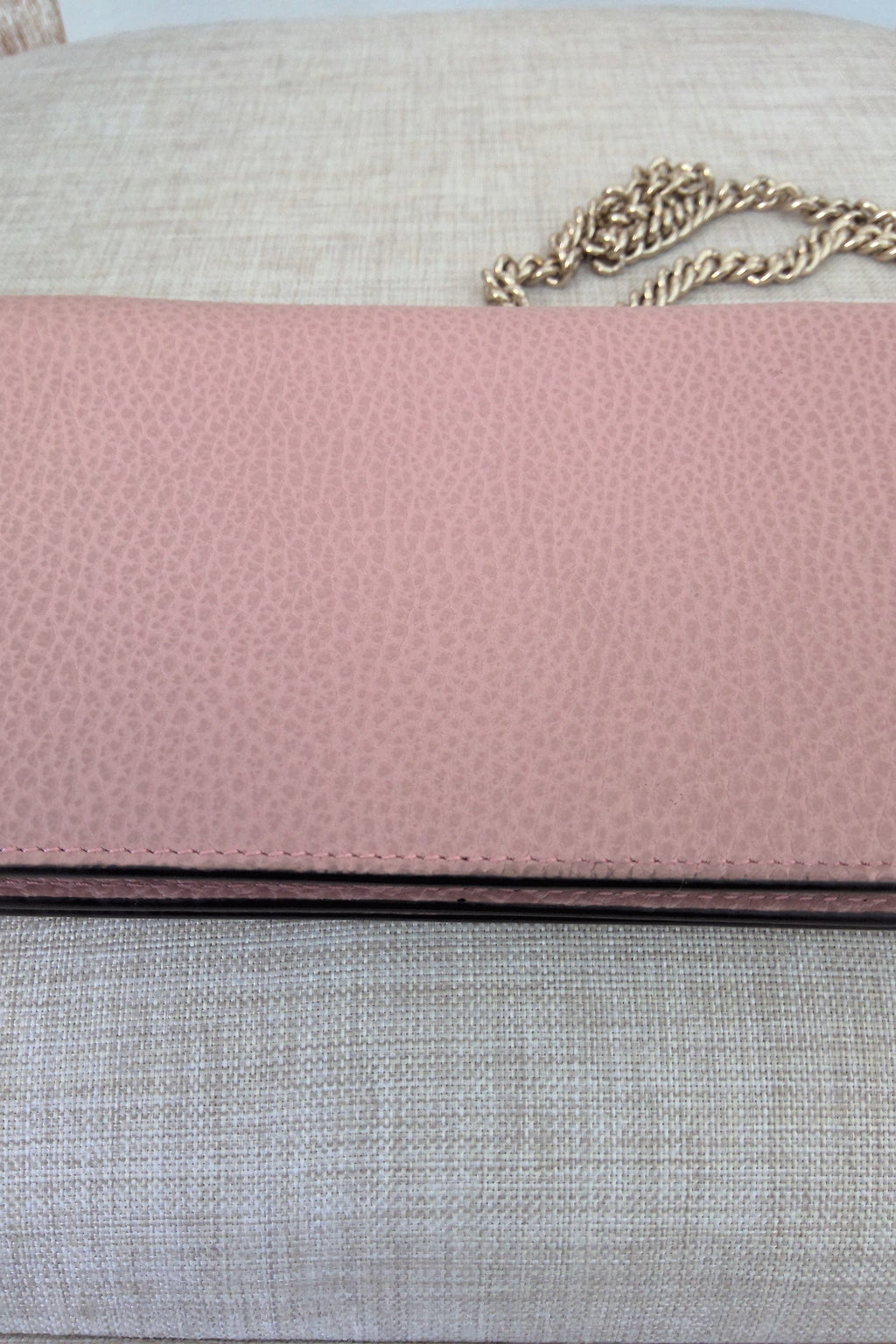 Close-up of a pink textured surface with a gold chain on a neutral background
