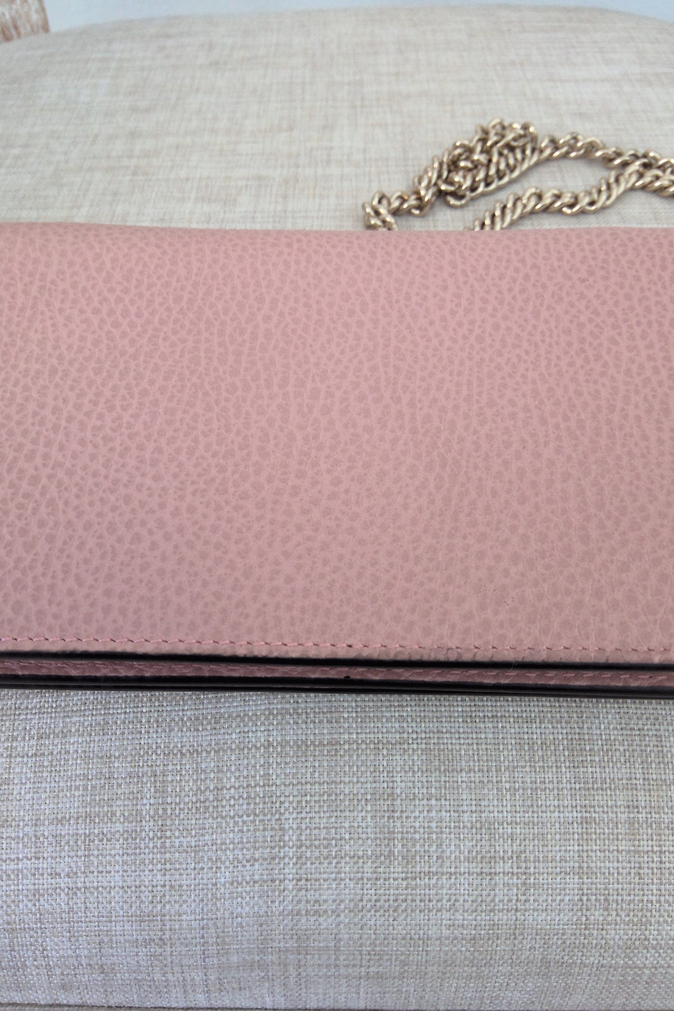 Close-up of a pink textured surface with a gold chain on a neutral background