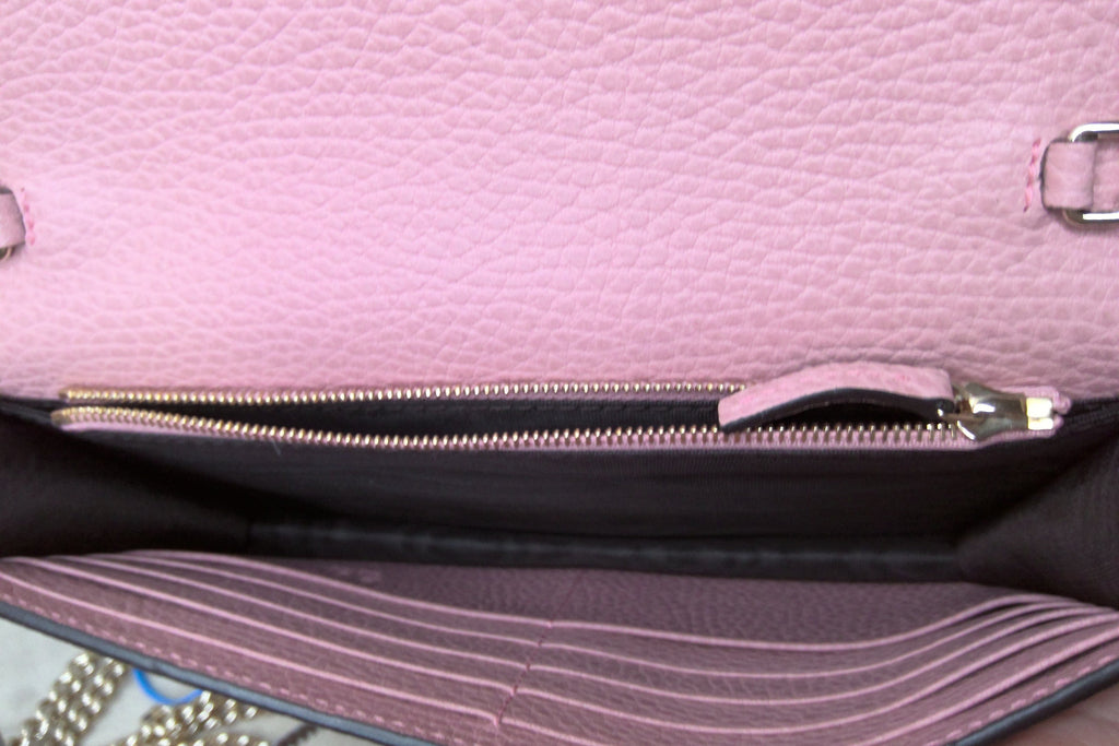 Close-up of a pink handbag with a zipper and strap.