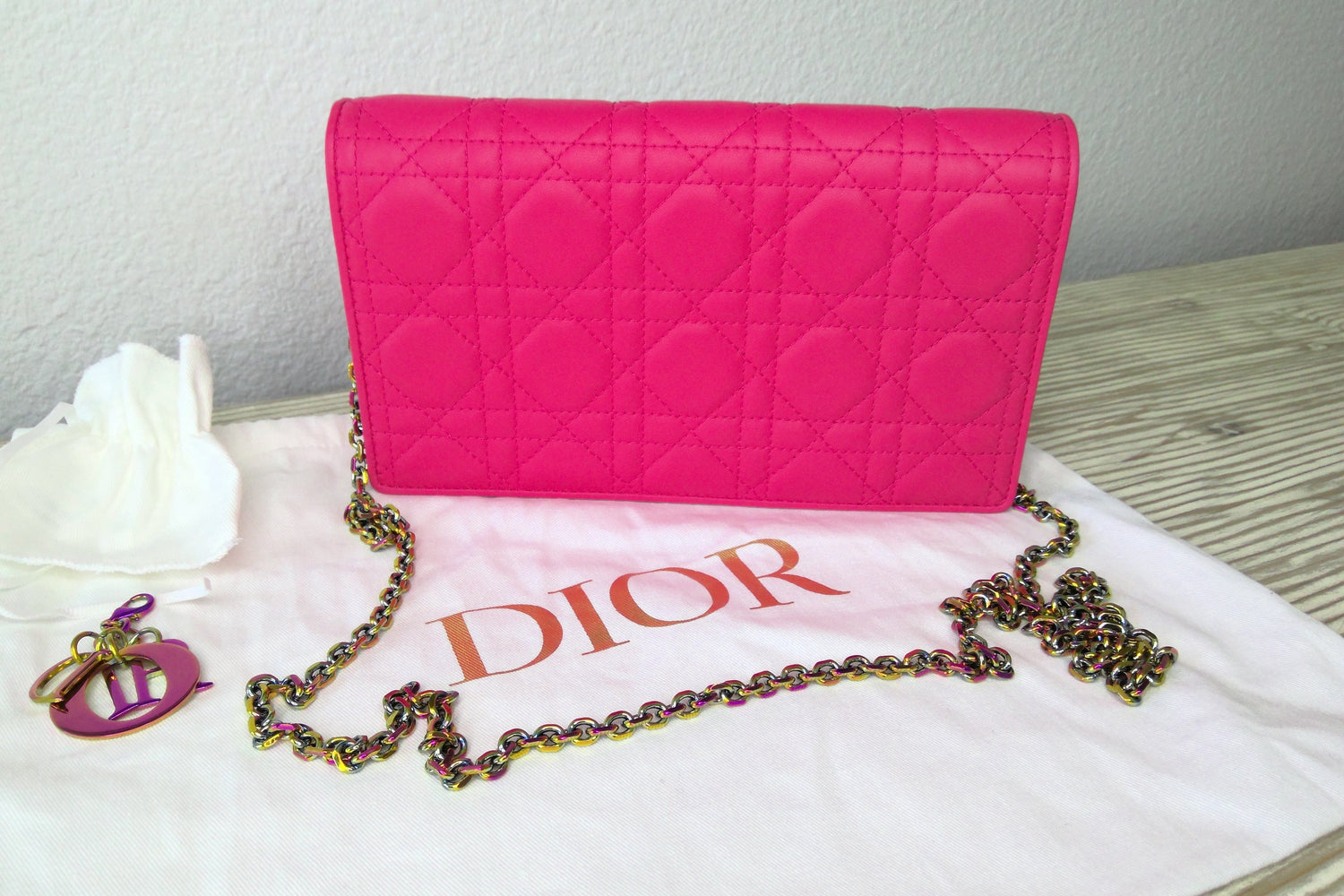 Pink quilted handbag with a chain strap on a white surface, featuring the Dior logo.