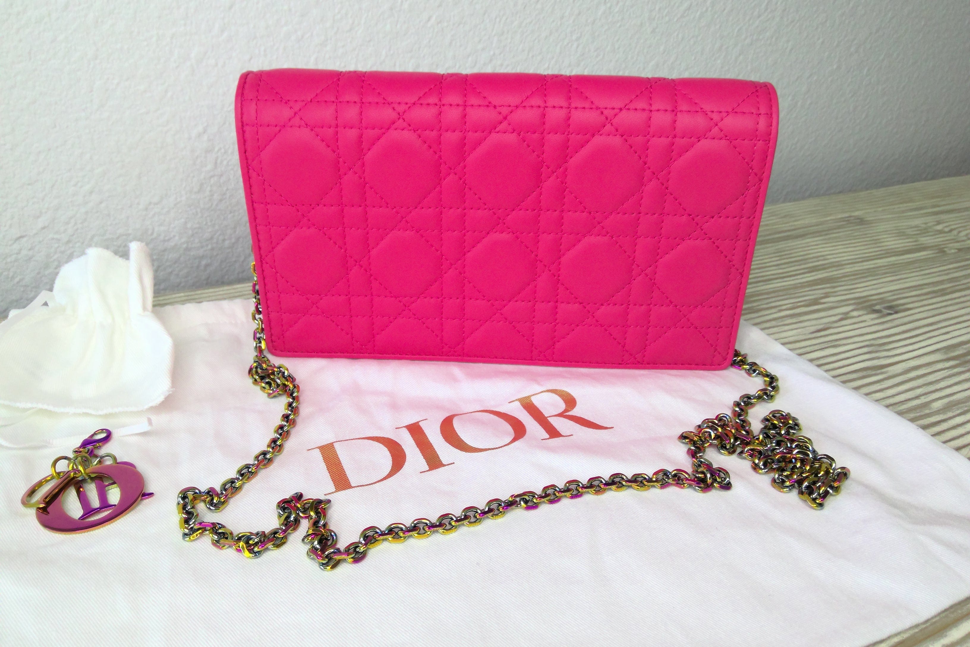 Pink quilted handbag with a chain strap on a white surface, featuring the Dior logo.