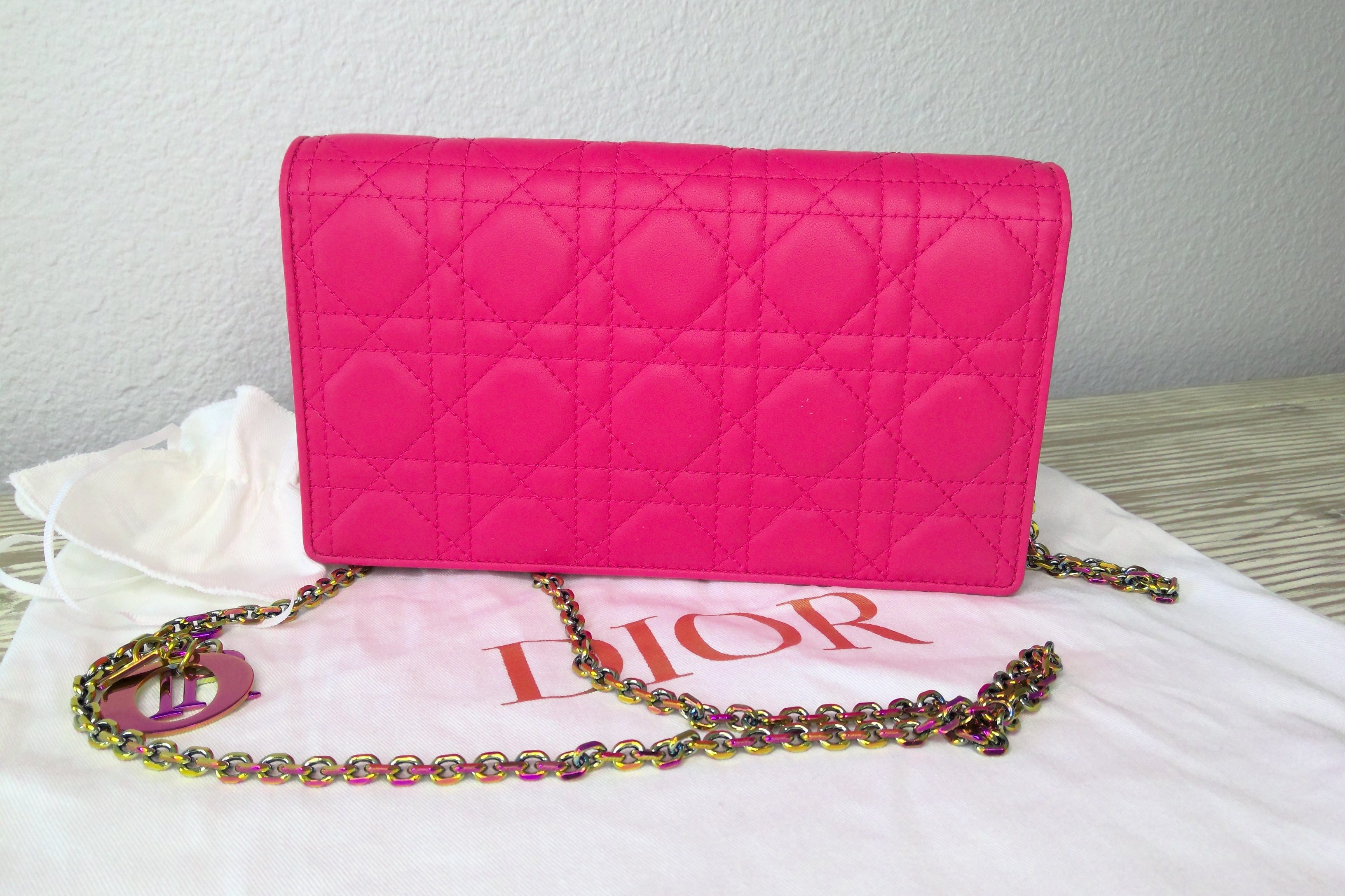 Pink quilted handbag with 'Dior' chain on a white surface