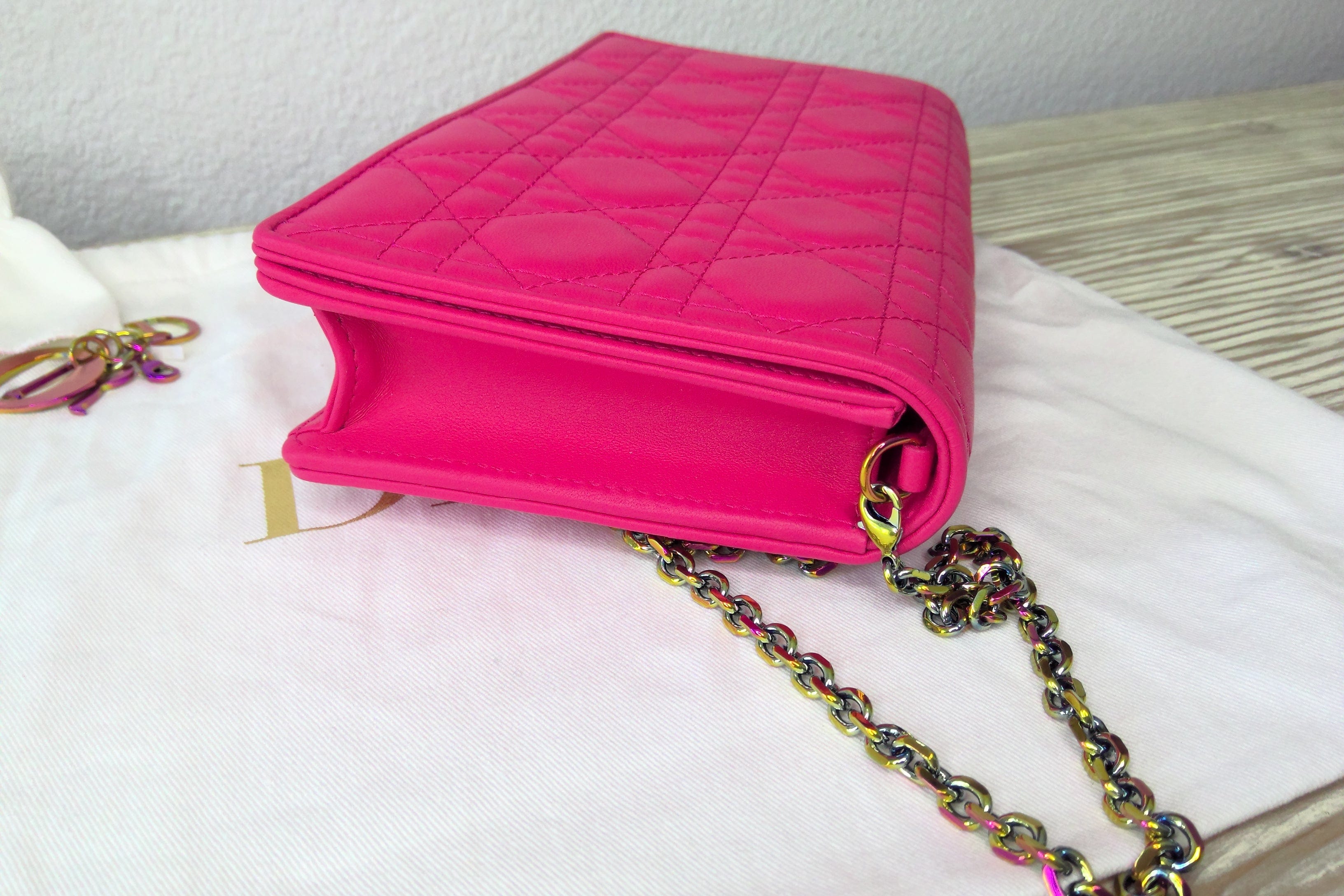 Pink quilted handbag with a chain strap on a white surface