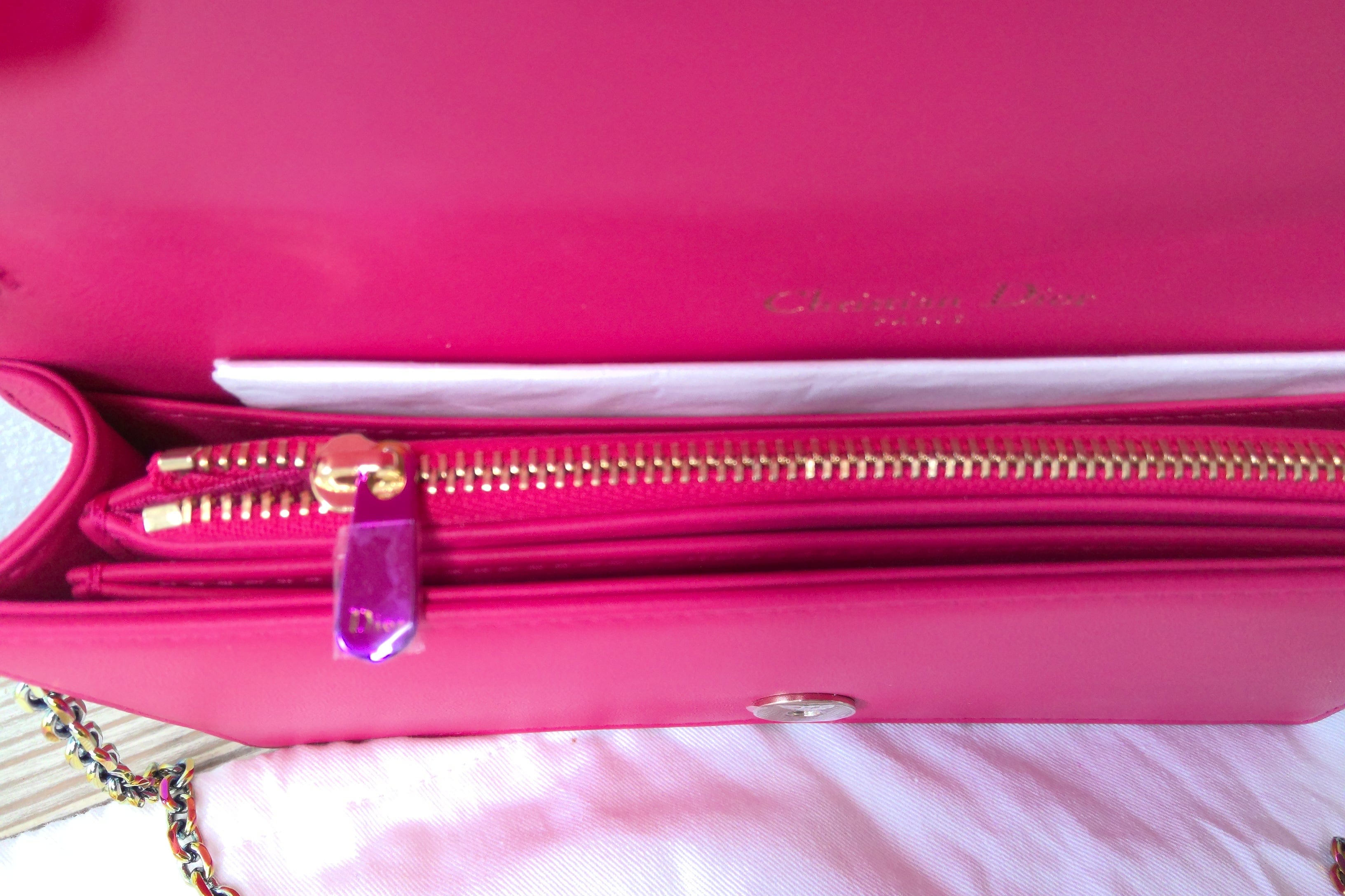 Close-up of a pink handbag with gold zipper and visible brand name.
