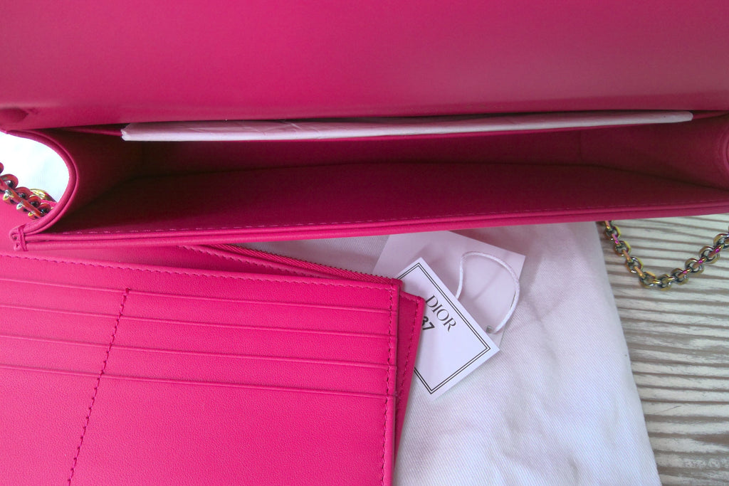 Pink wallet with a visible brand tag on a white surface