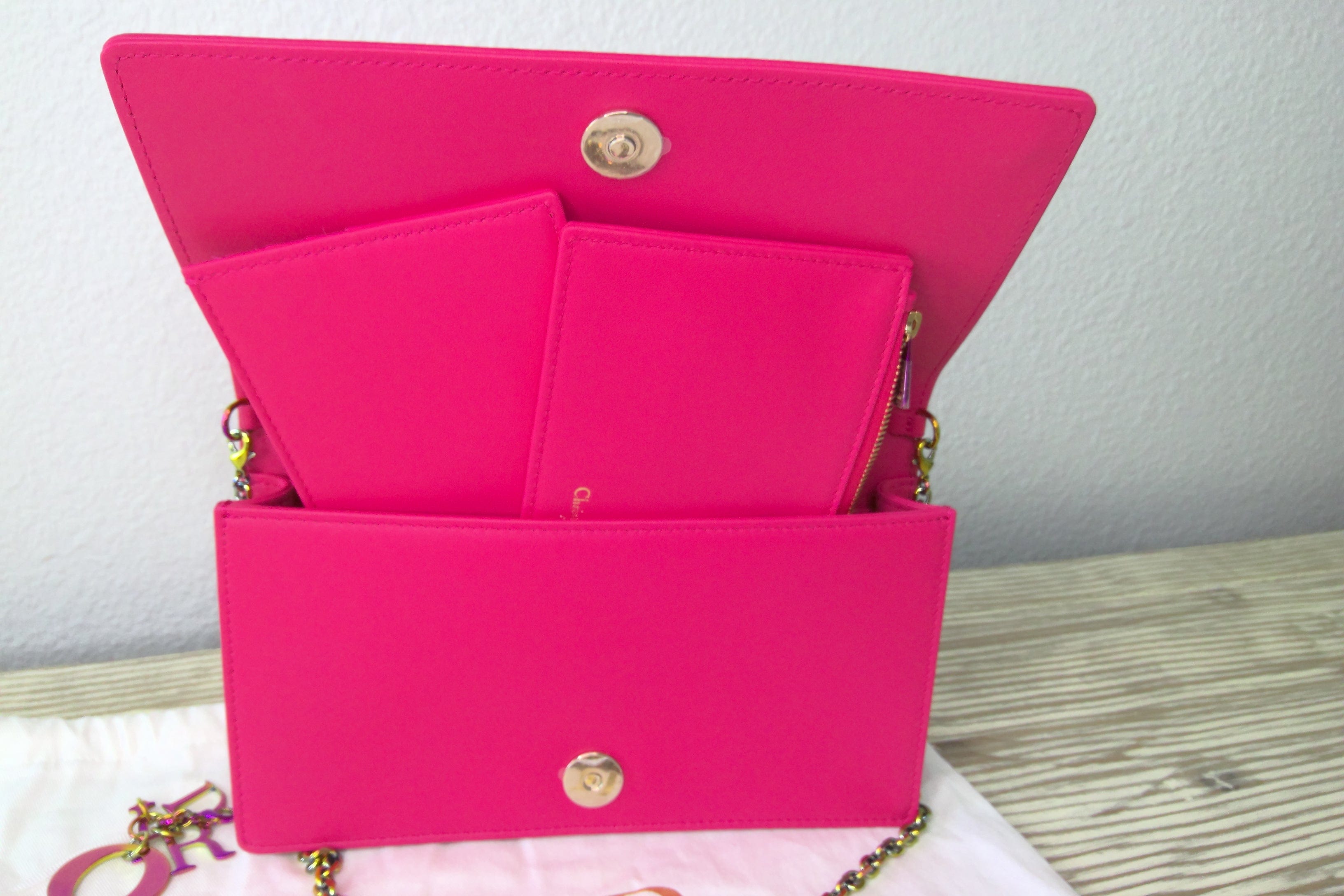 Pink handbag with gold clasp on a light wooden surface